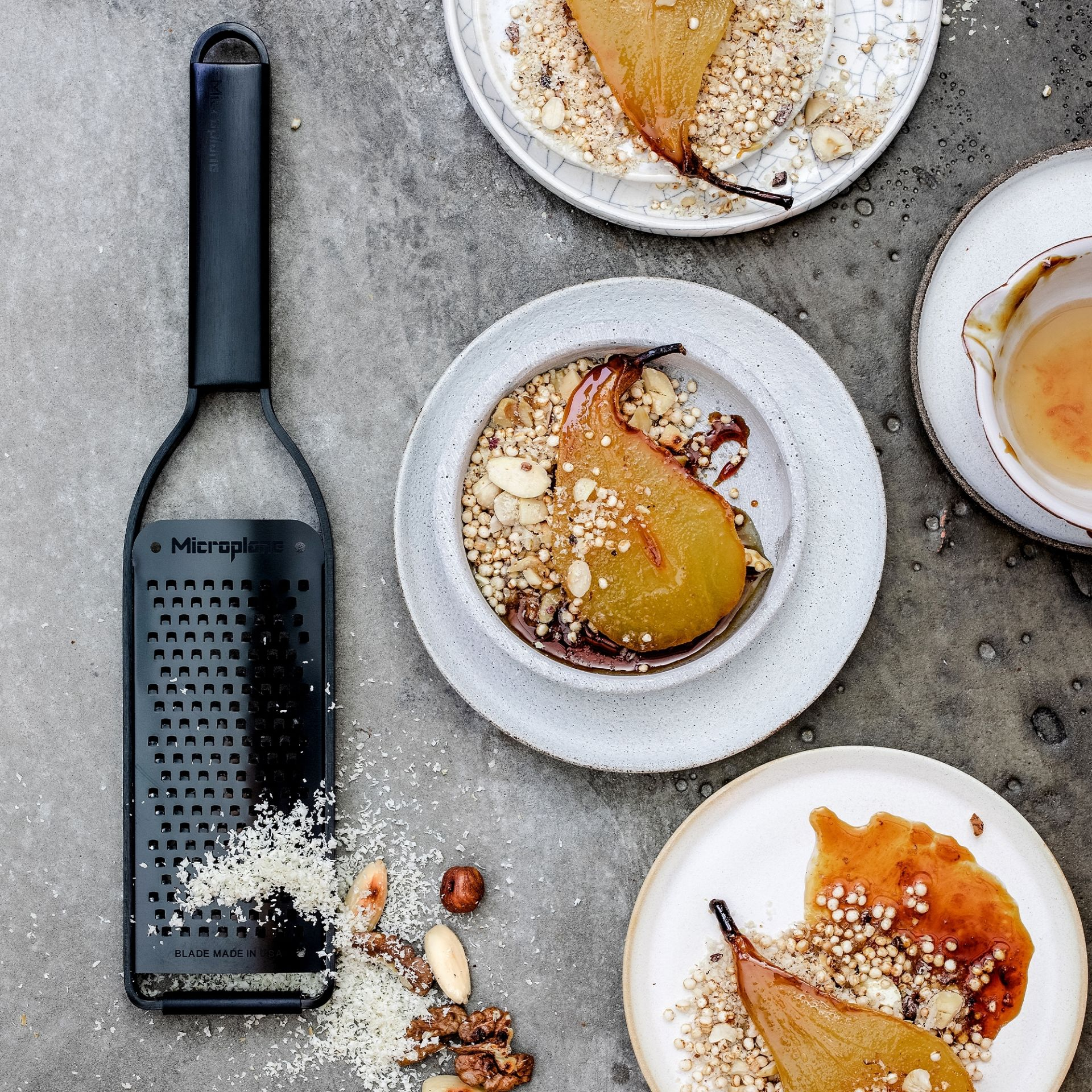 Czarna tarka i pieczone gruszki z dodatkami na szarej kamiennej powierzchni.