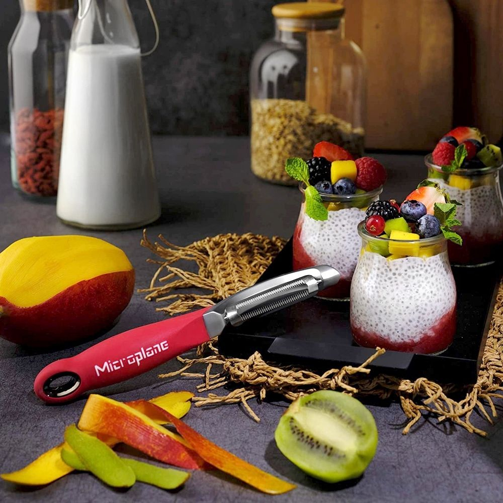 Czerwona obieraczka z owocami i deserami na ciemnej powierzchni.