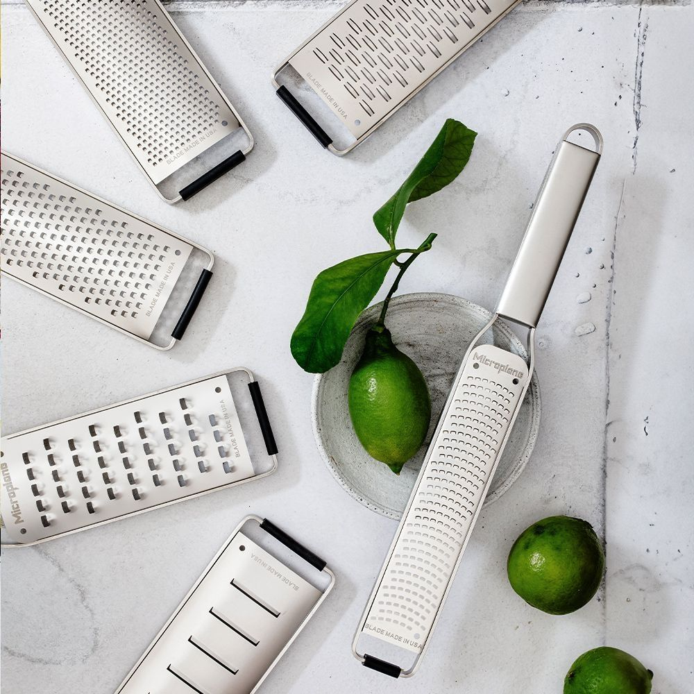 Lime, grattugia, foglie su una superficie. Sono visibili più grattugie e lime.