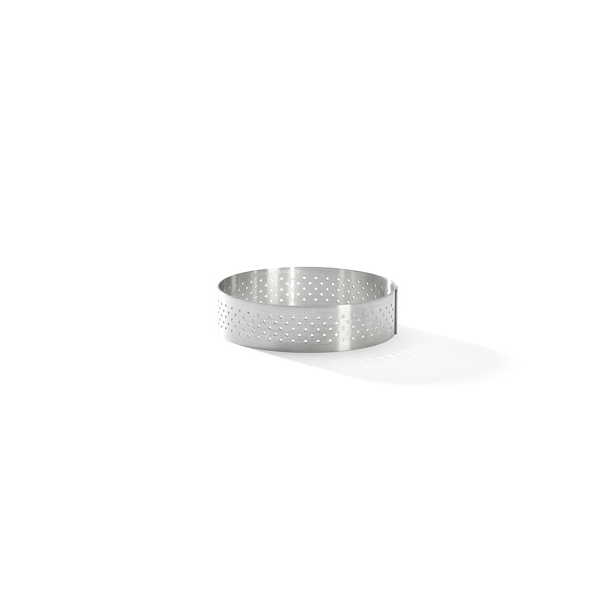 Ein Metallring mit kleinen Löchern. Es liegt auf einer weißen Oberfläche.