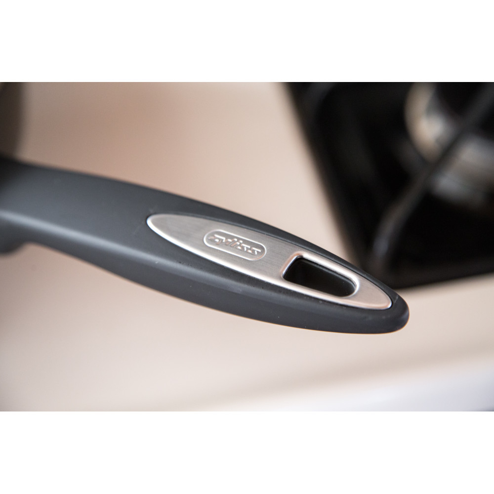 Zbliżenie uchwytu patelni z metalowym logo.