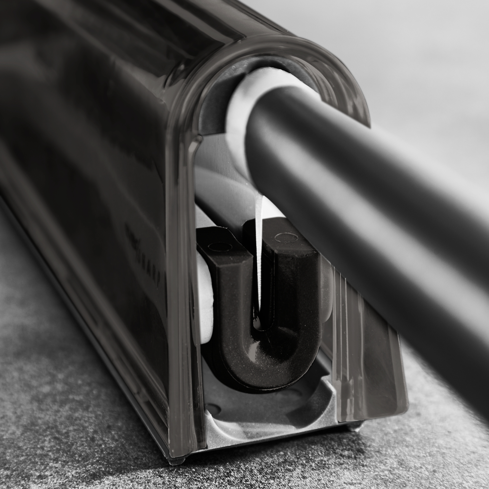 Przezroczysta plastikowa ostrzałka do noży z czarnym uchwytem. Nóż jest w ostrzałce.