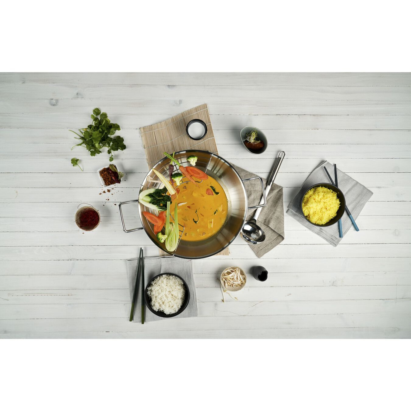 Widok z góry na danie z jedzeniem i przyborami, otoczone składnikami. Ustawienie jest stylowe.