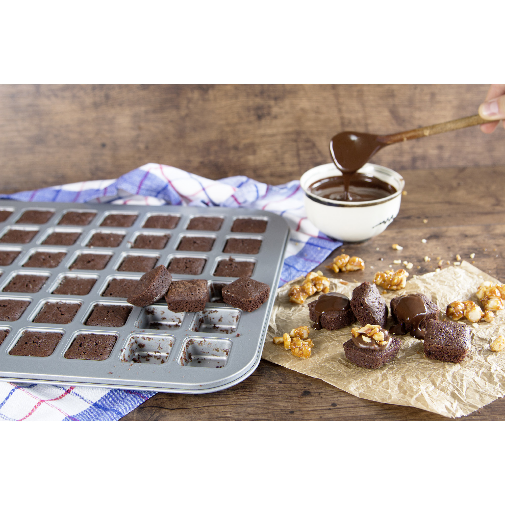 Brownies in der Pfanne und auf Pergament, mit einer Schüssel geschmolzener Schokolade.