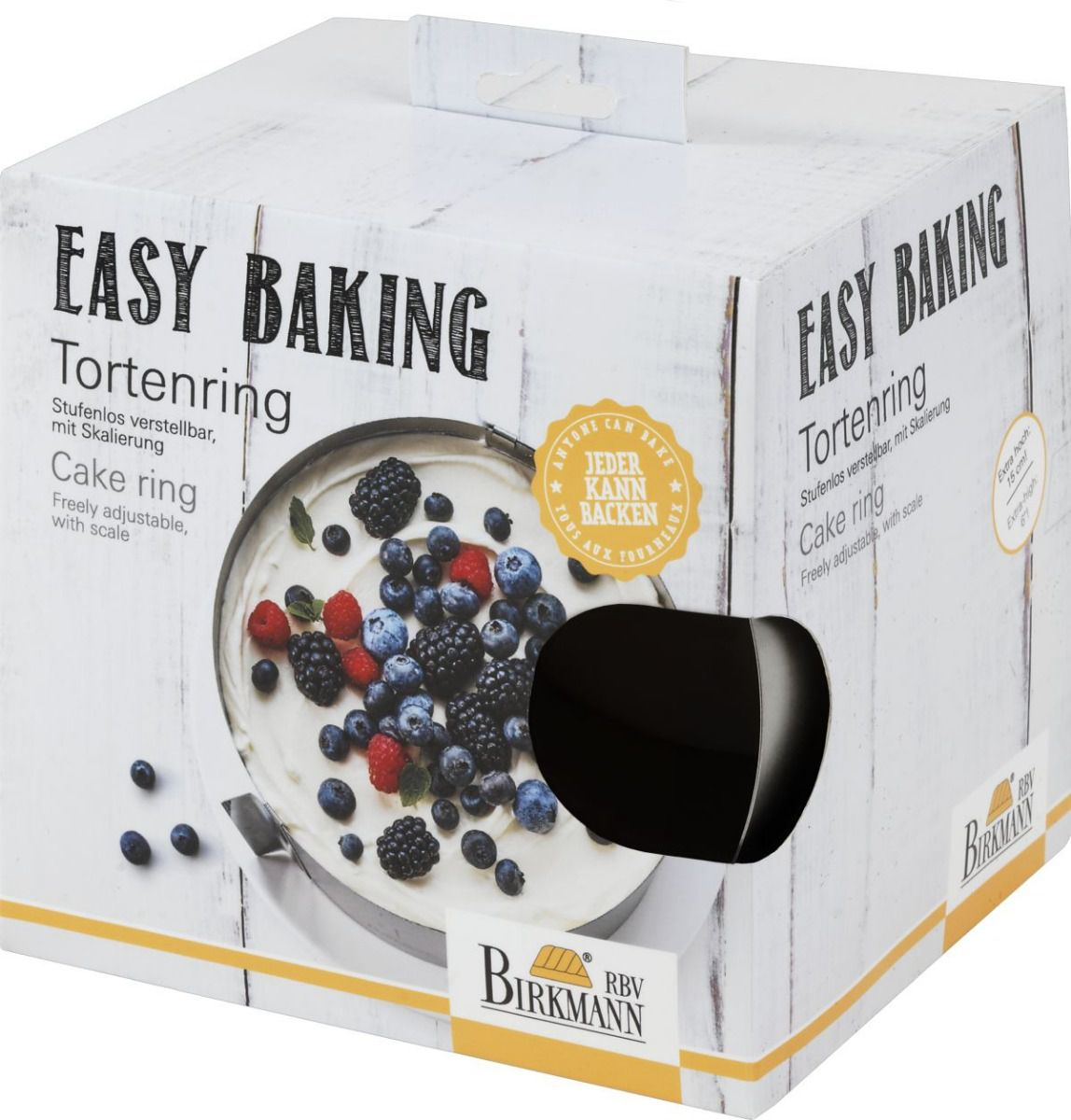 Eine Tortenring-Box mit Kuchenbild, Tortenring davor. Weiße und helle Holzfarbenbox.