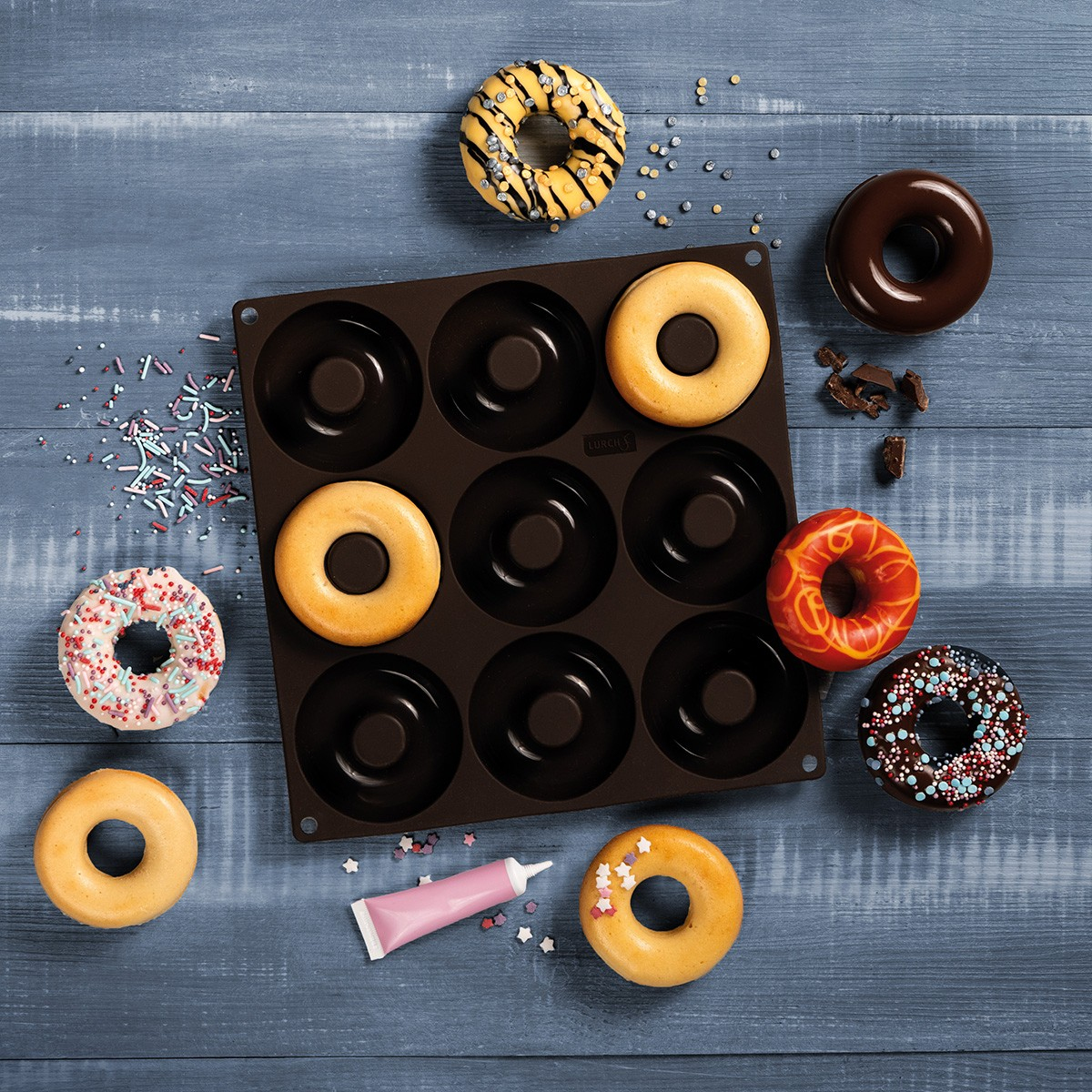 Donut-Tablett mit Donuts und Dekorationen. Einige Donuts sind verziert. Holztisch.