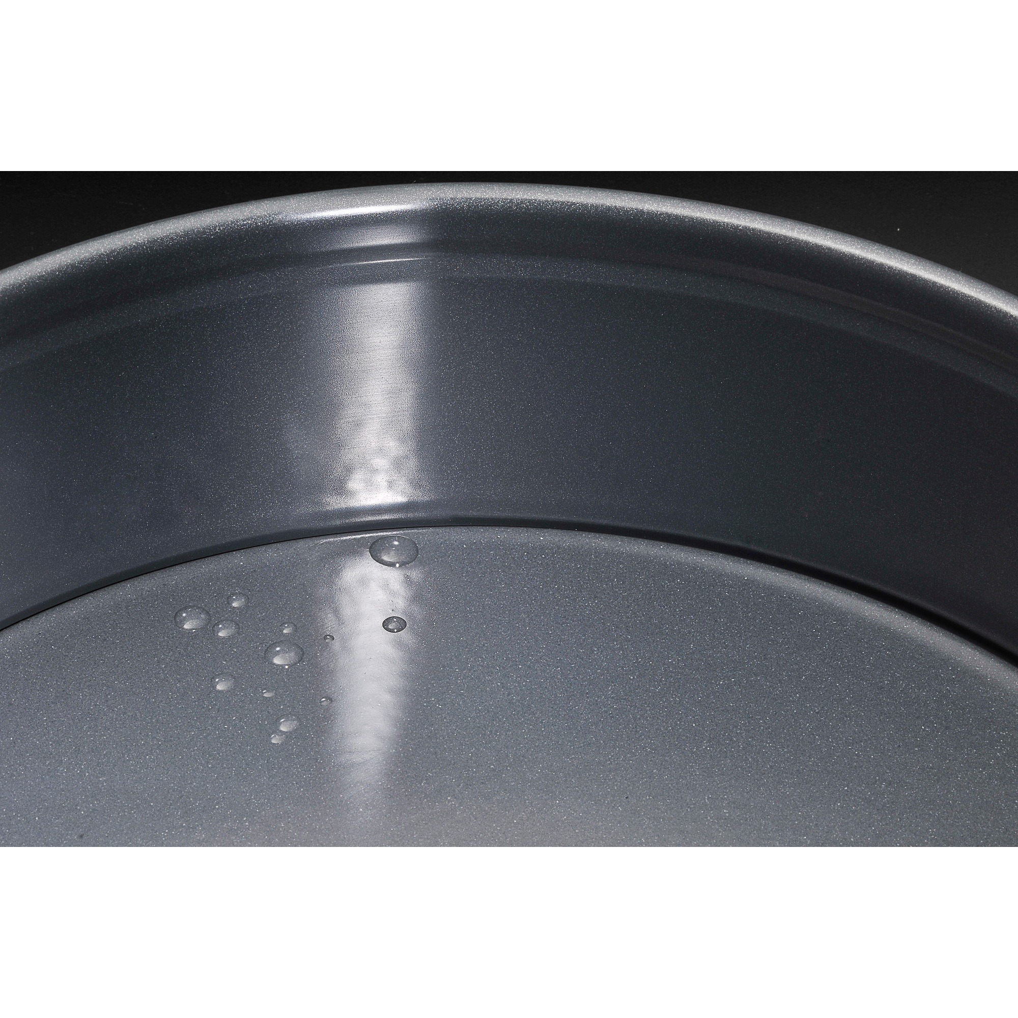 Zbliżenie szarej blachy do pieczenia z kroplami wody. Ciemne tło.