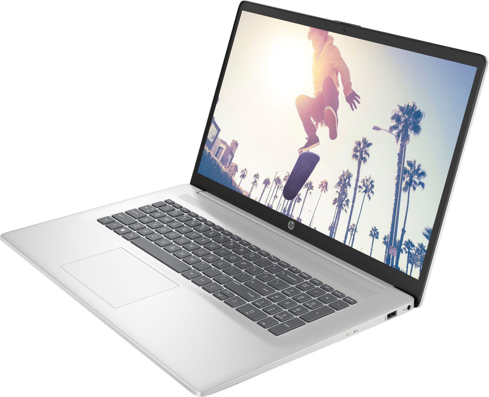Silberner Laptop geöffnet, zeigt einen Skater in der Luft. Palmen im Hintergrund. Tastatur und Touchpad sind sichtbar.