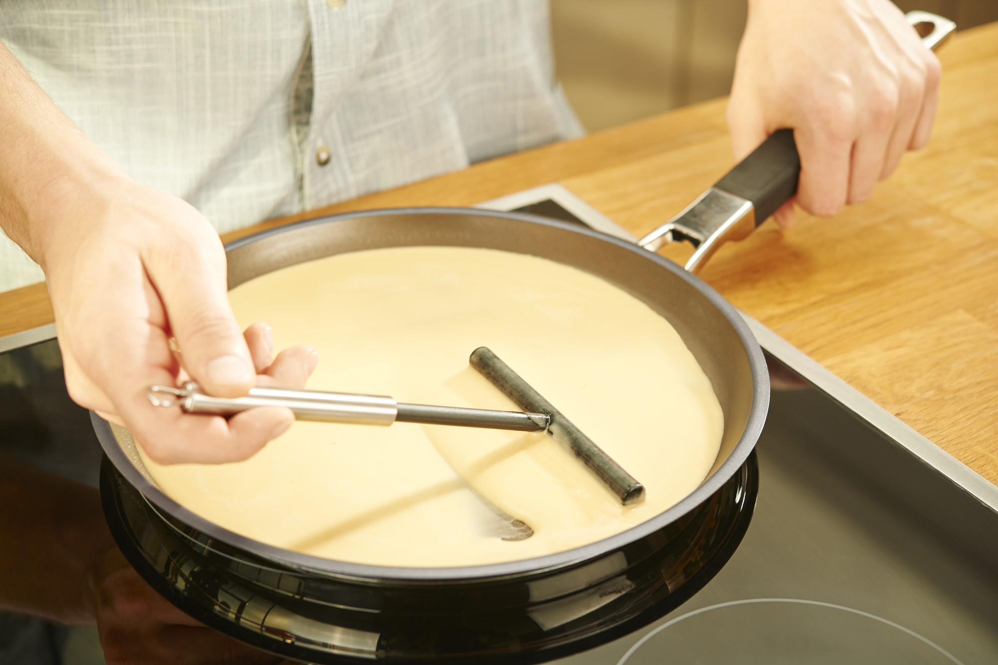Ein Pfannkuchen wird in einer Pfanne gebraten. Eine Person verwendet einen Spatel.