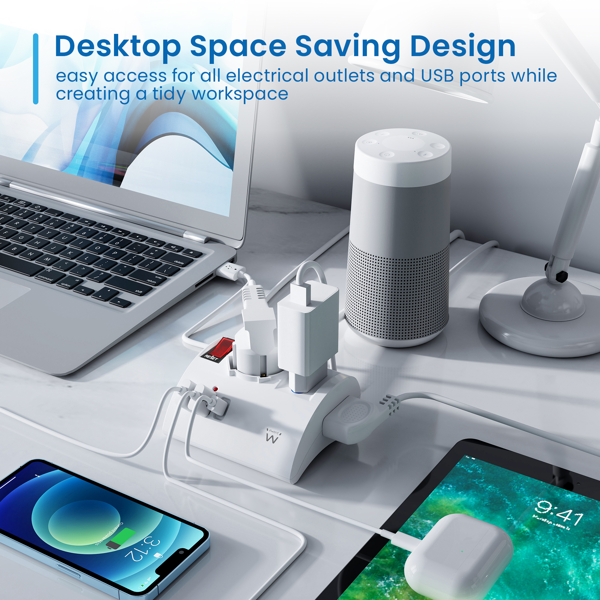 Przestrzeń robocza z laptopem, tabletem, głośnikiem, telefonem i listwą zasilającą.