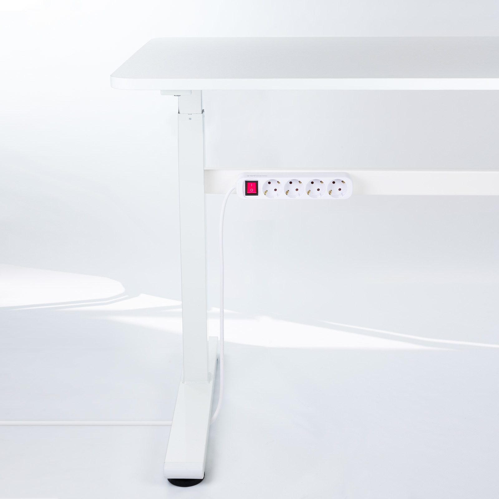 Witte bureau met een witte stekkerdoos bevestigd. De stekkerdoos heeft een rode schakelaar.