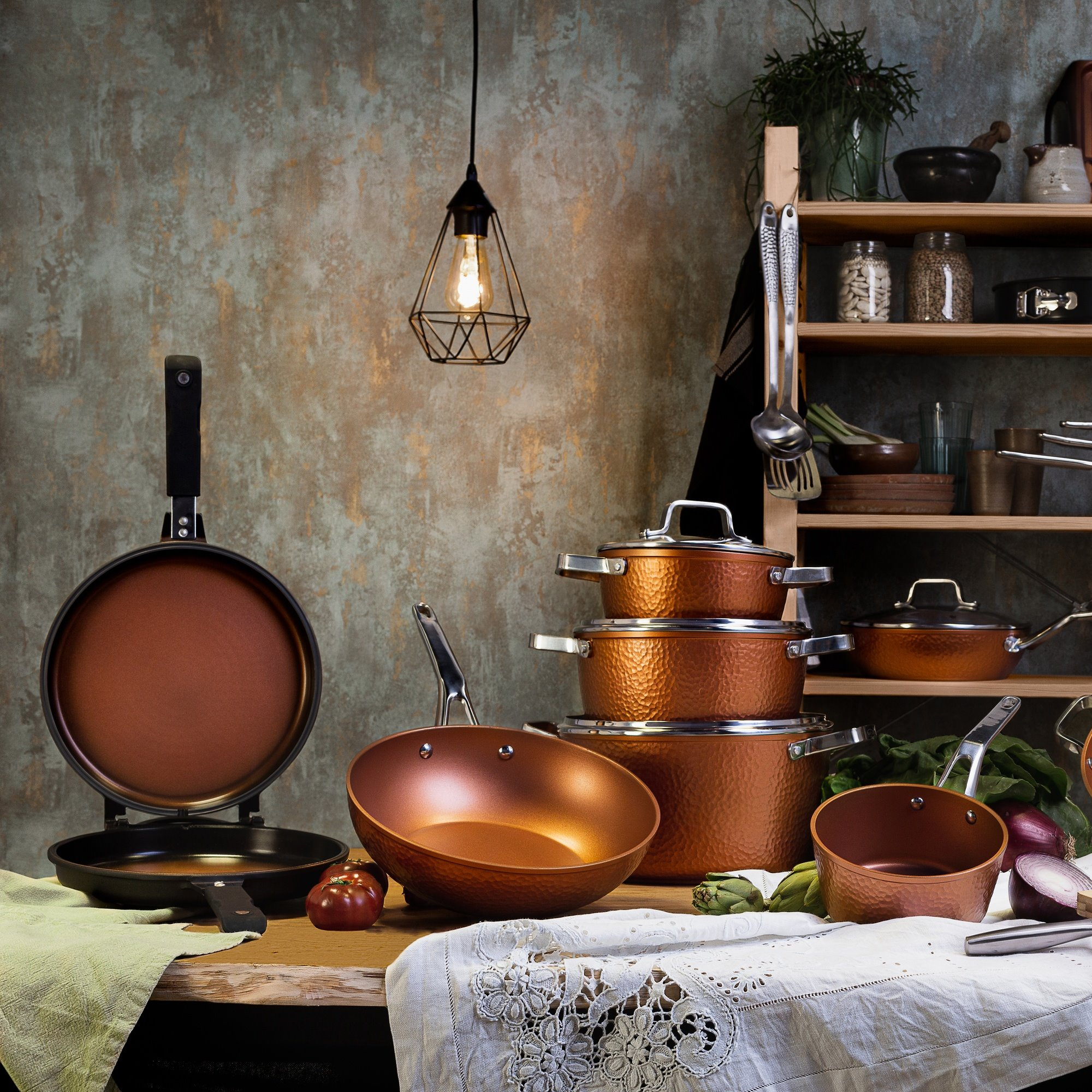 Escena de cocina: utensilios de cocina de cobre, mesa, lámpara, estantes.