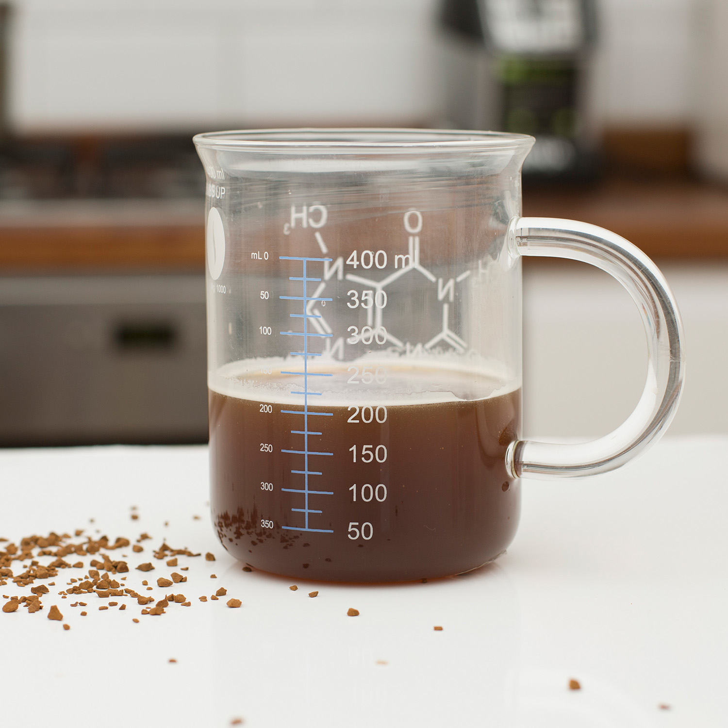 Szklany zlewka z kawą i uchwytem. Wydrukowano słowo Kofeina i strukturę chemiczną.