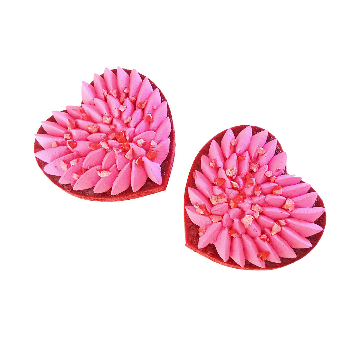 Zwei herzförmige Gebäckstücke mit rosa Zuckerguss und roten Streuseln. Weißer Hintergrund.
