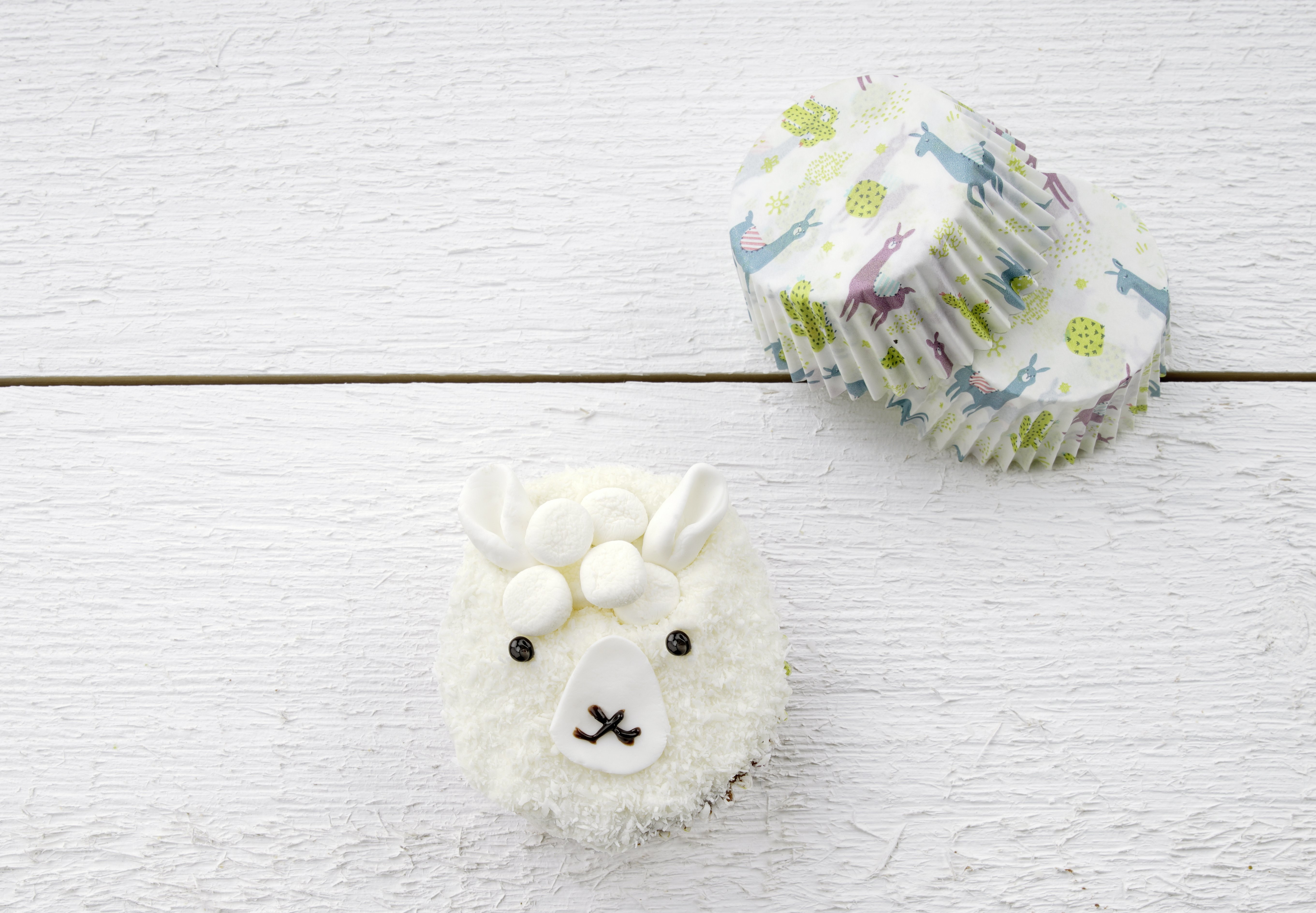 Lama-Cupcake mit Marshmallow und Kokosnuss und zwei Cupcake-Formen.