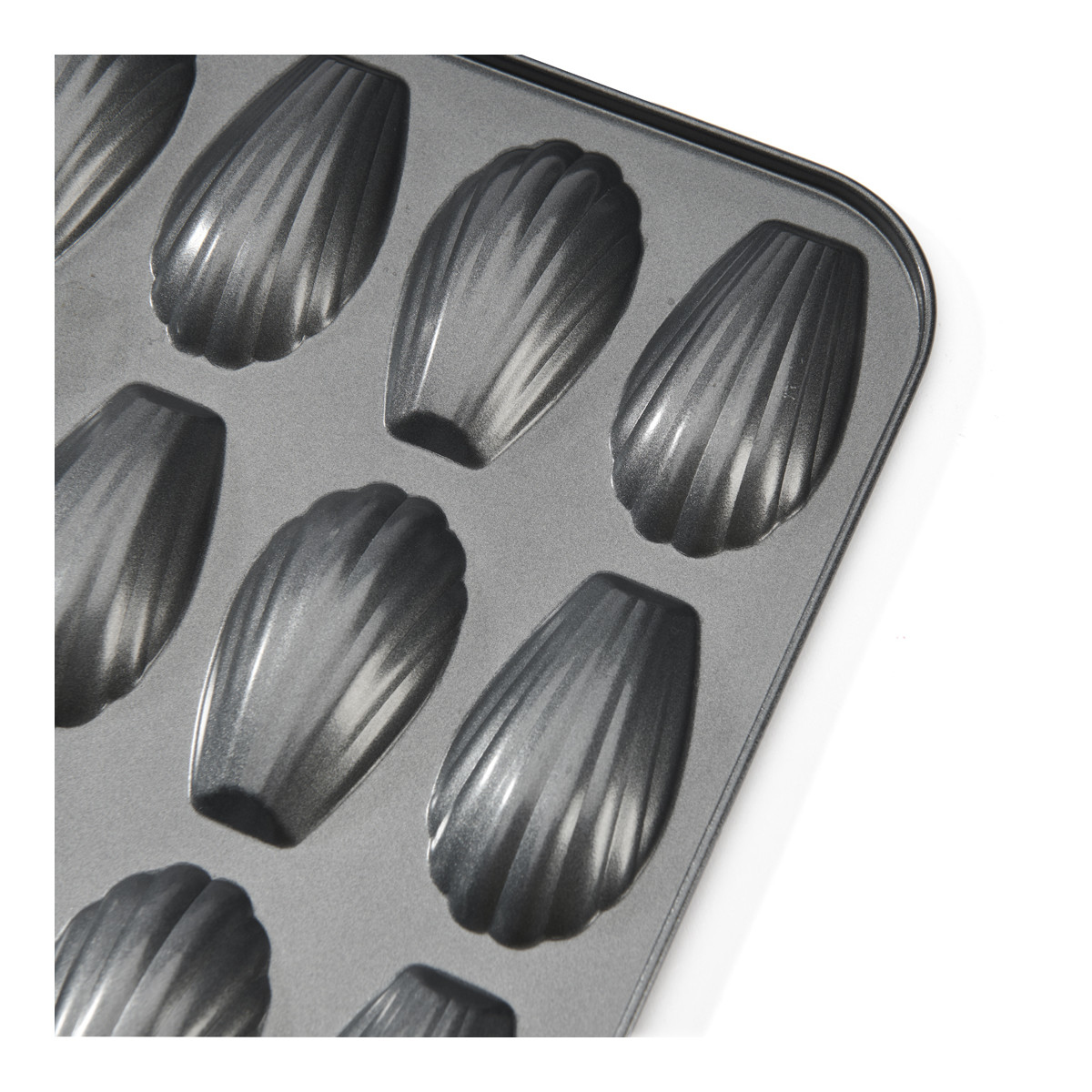 Zbliżenie na formę do madeleine z 12 foremkami. Powierzchnia jest ciemnoszara.