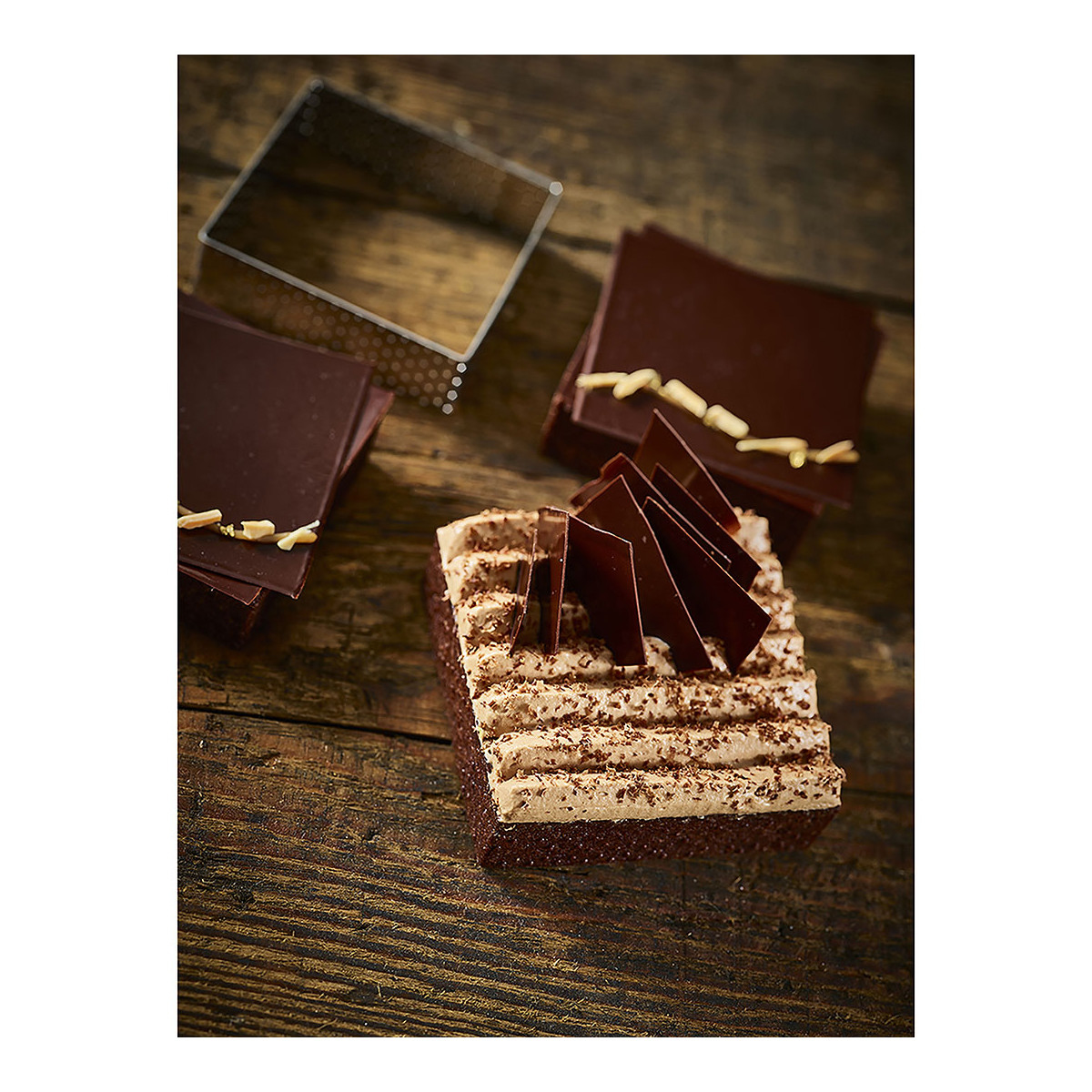 Ein Schokoladenkuchen mit Schokoladenstücken und Sahne auf Holzoberfläche.