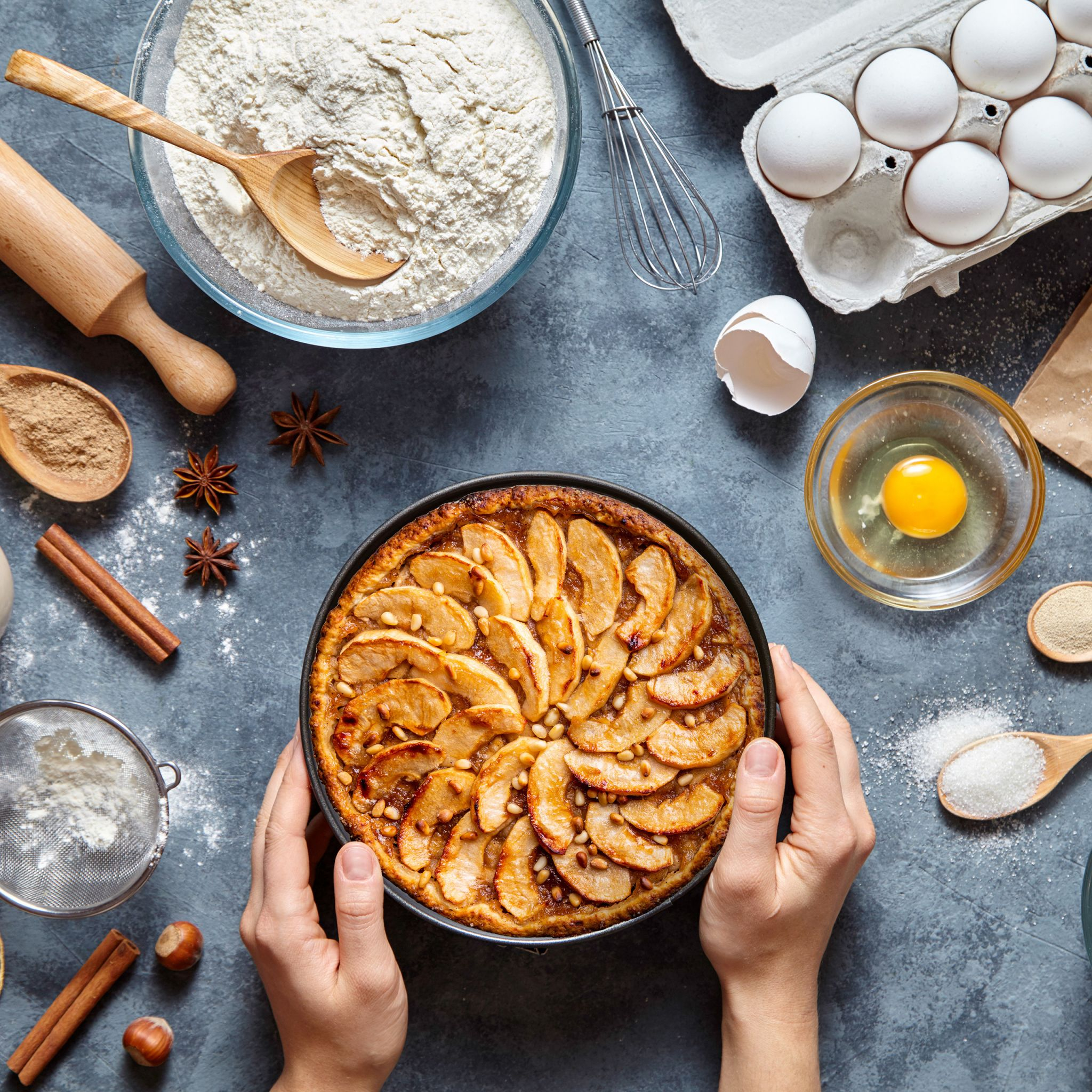 Draufsicht auf Zutaten zum Backen. Apfelkuchen in der Mitte, Mehl, Eier usw.