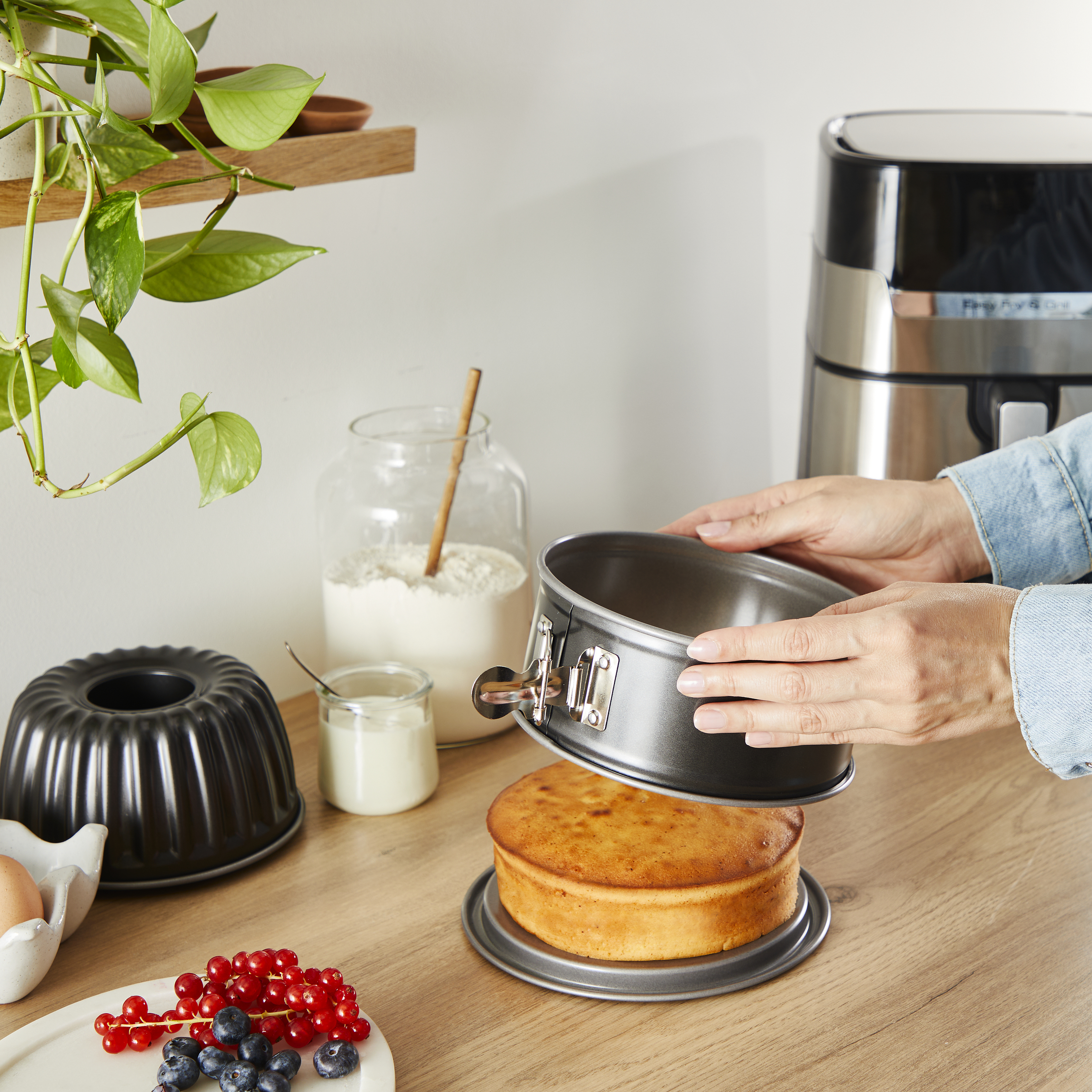 Osoba składająca ciasto. Artykuły do pieczenia na drewnianej powierzchni. Biała ściana.