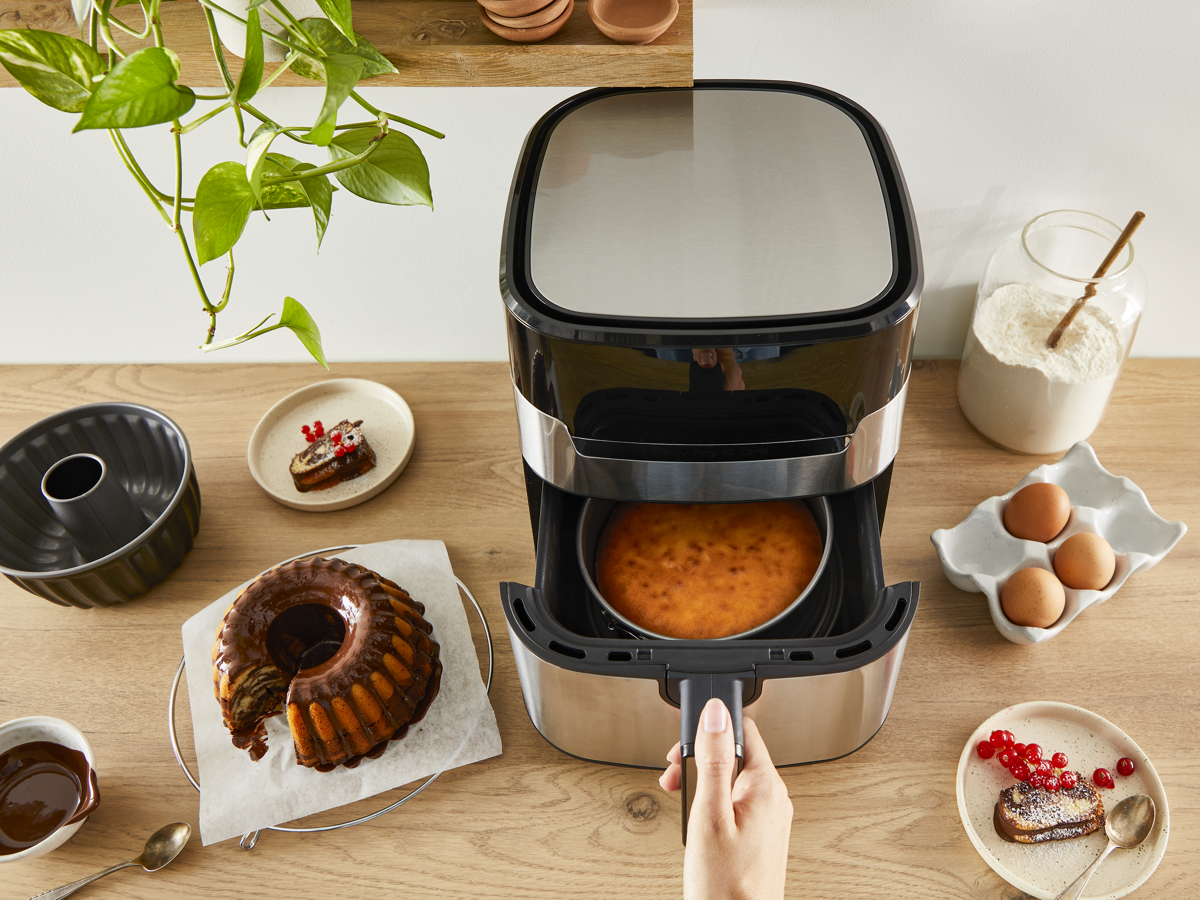 Frytownica beztłuszczowa, ciasta, składniki i przybory są na drewnianej powierzchni, tworząc scenę gotowania.