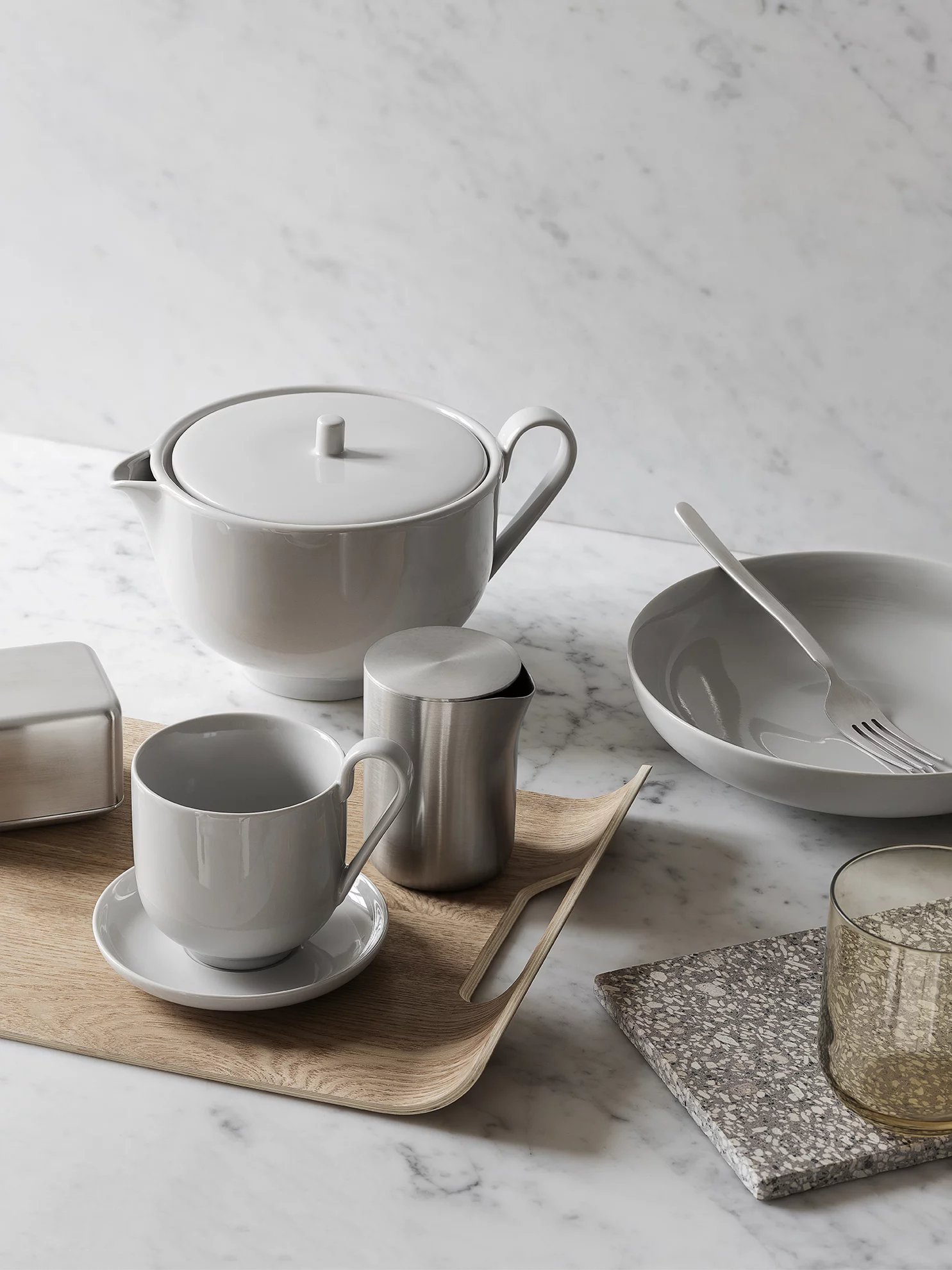 Tischgedeck mit Teekanne, Tasse, Schüssel, Tablett und Utensilien.