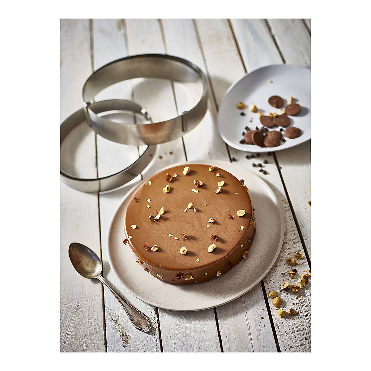 Ciasto czekoladowe z orzechami i dwoma formami pierścieniowymi na białej drewnianej powierzchni.