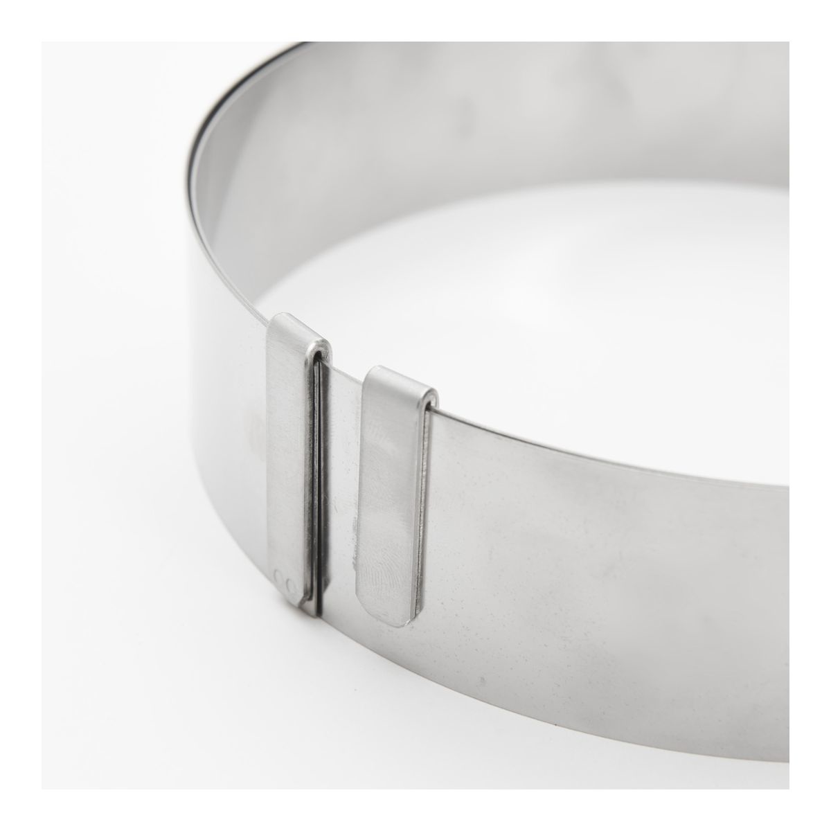 Metalowy pierścień z zapięciem na białej powierzchni, zbliżenie obiektu.