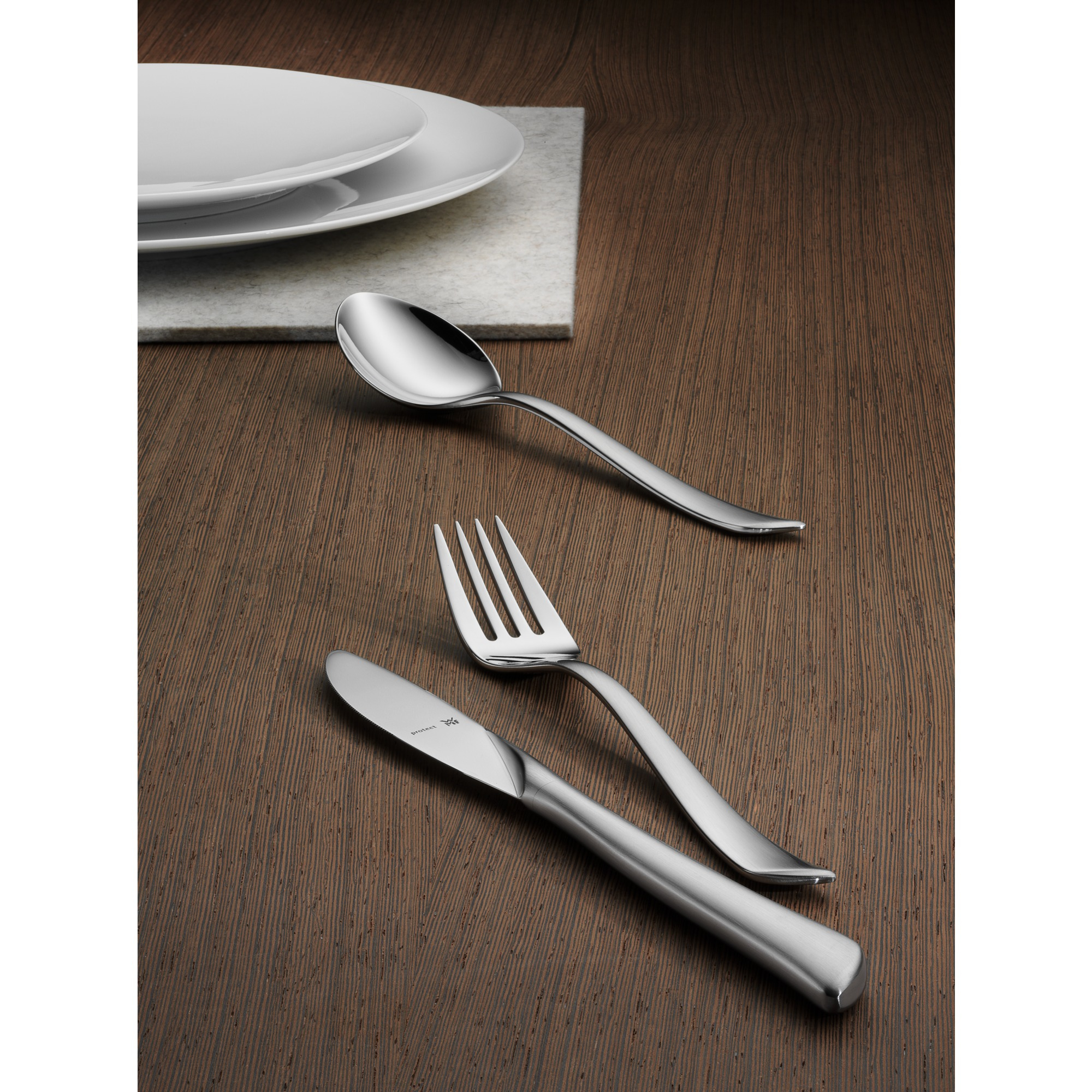Silberbesteck auf einem Holztisch: Gabel, Messer und Löffel.