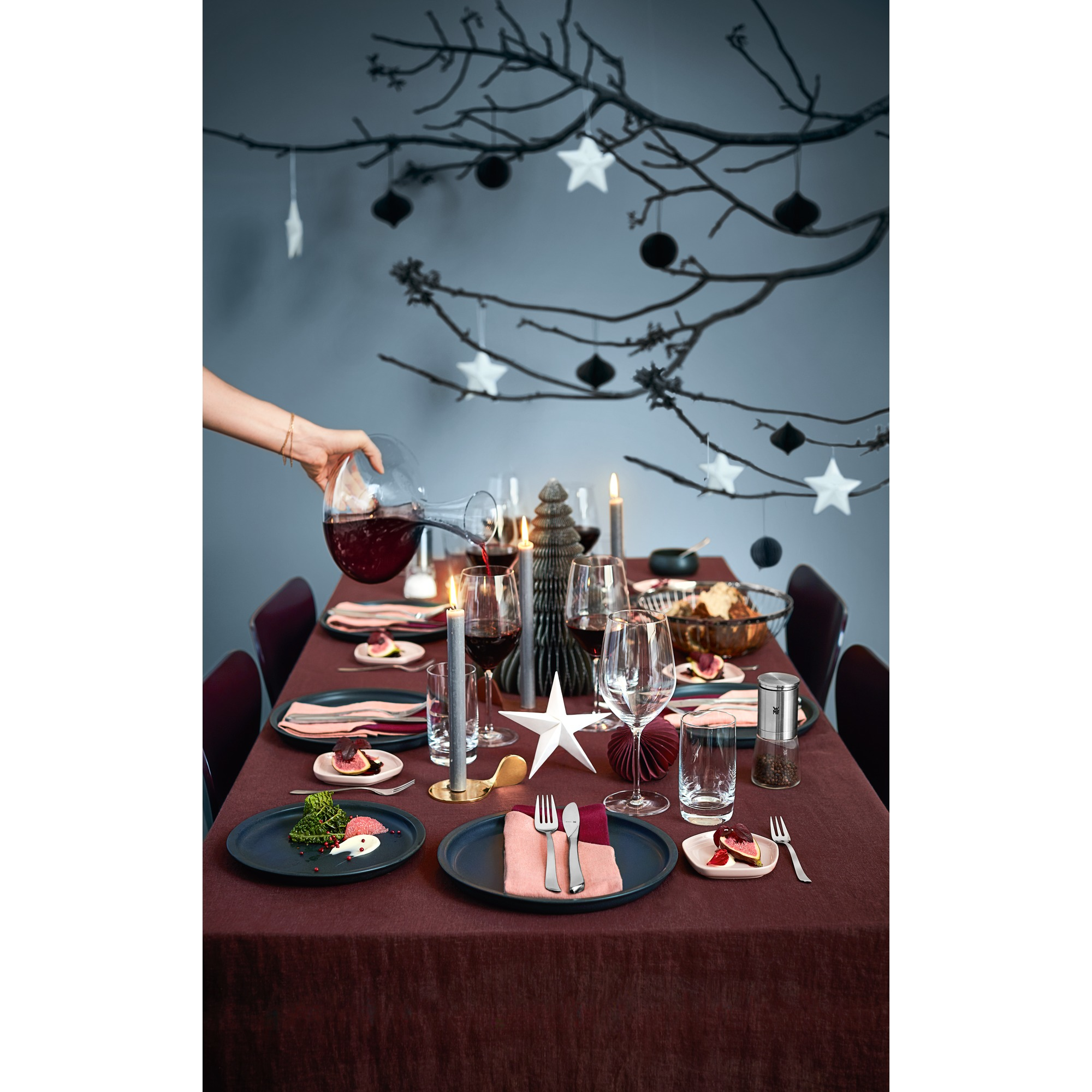 Eine Tischdeko mit Tellern, Gläsern, Besteck, Kerzen und Essen. Dunkler Hintergrund.