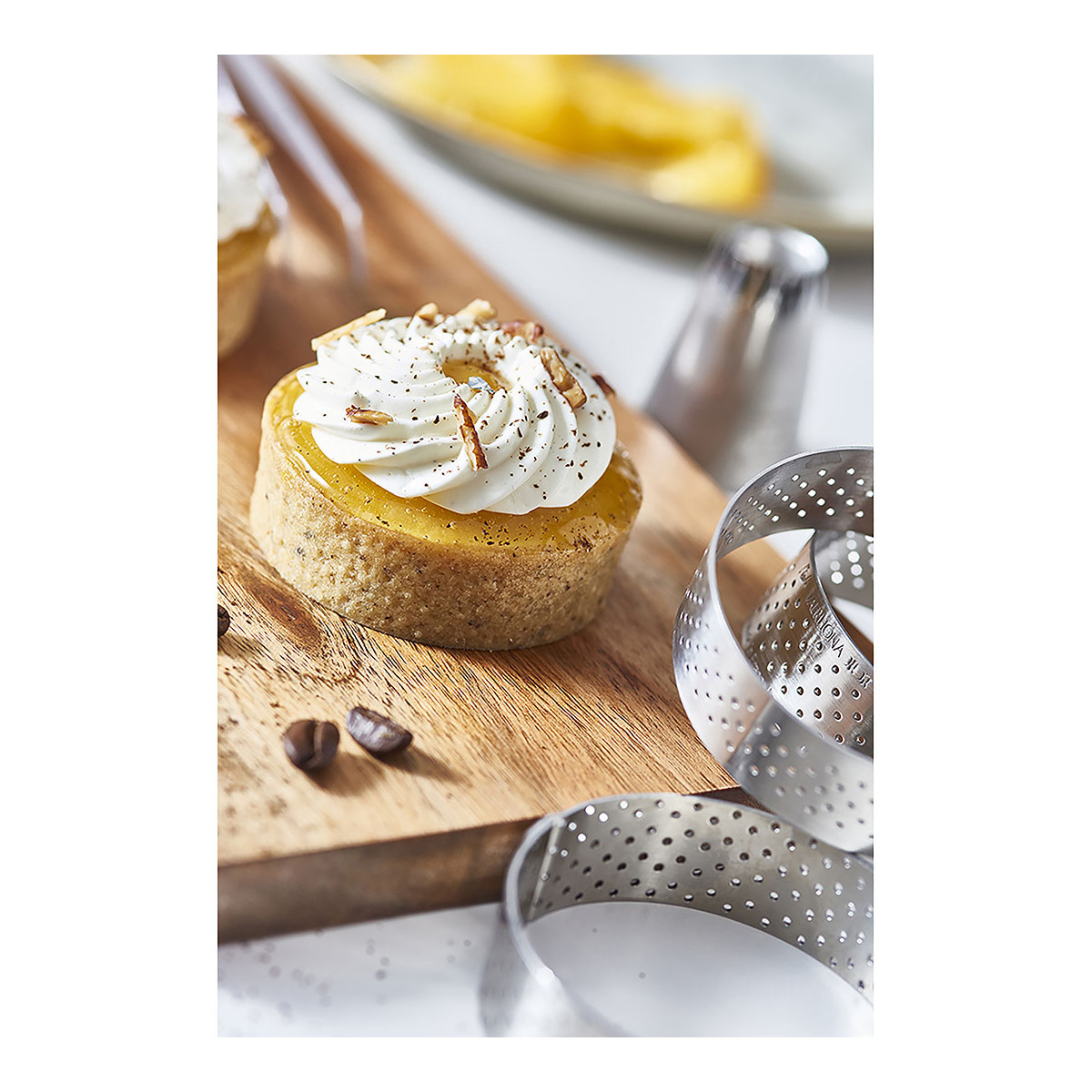 Ein Dessert mit weißer Creme und Nüssen auf einem Holzbrett, mit zwei silbernen Ringen.