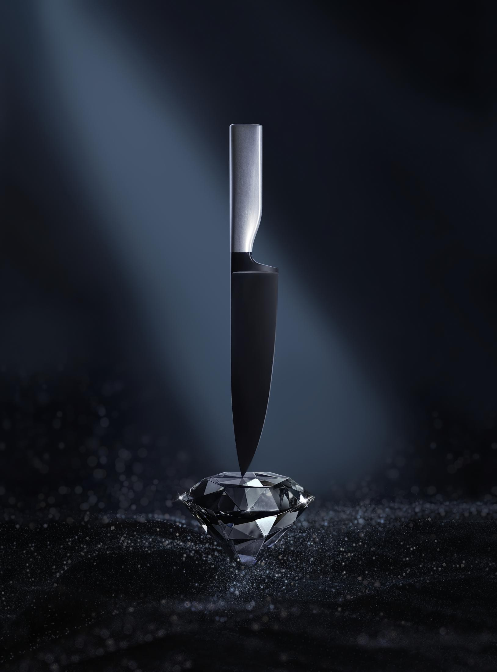Schwarzes Messer durchbohrt einen Diamanten auf dunklem Hintergrund mit blauem Scheinwerfer.