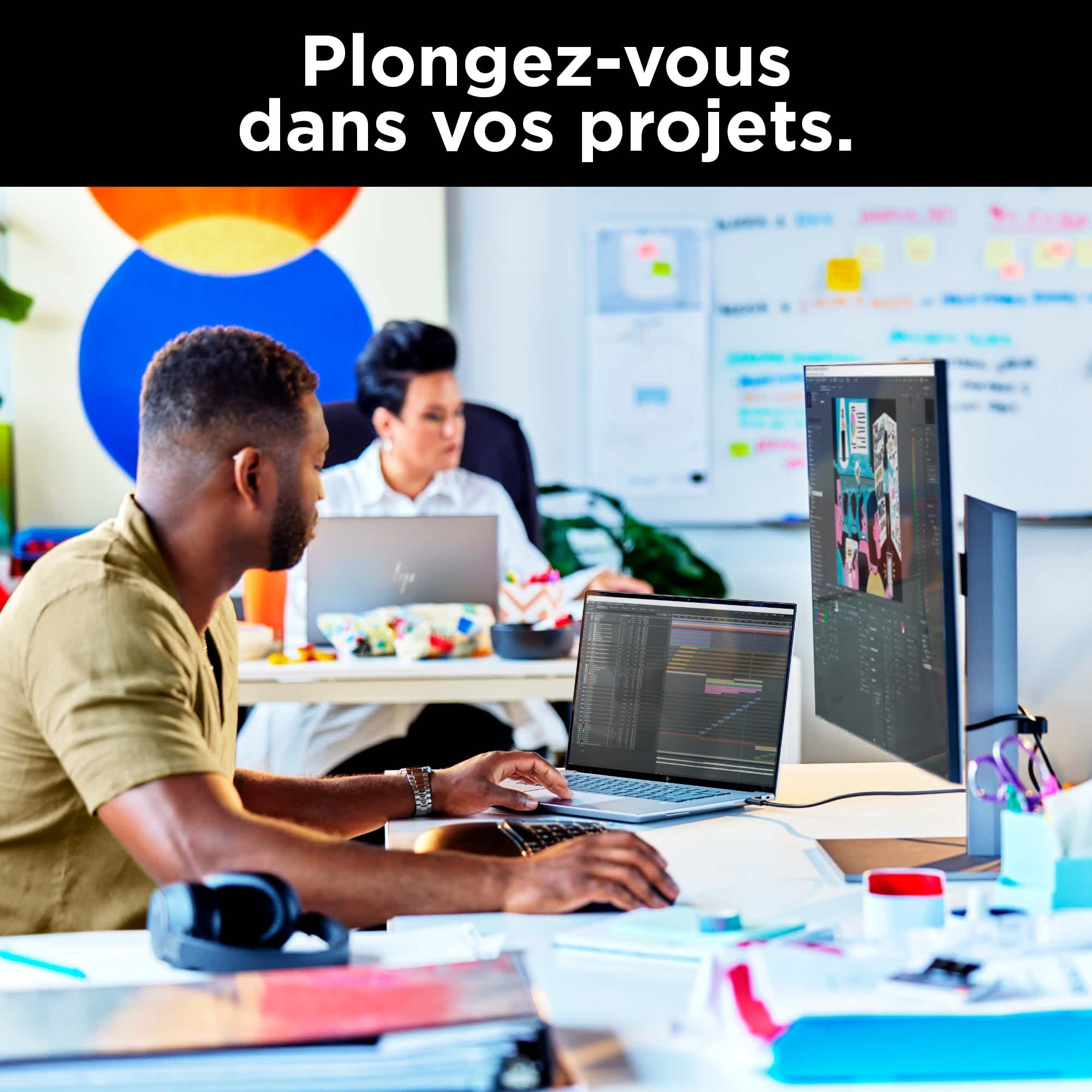 Dwie osoby pracują na laptopach. Monitor wyświetla grafikę. Tekst: Zanurz się w swoich projektach.