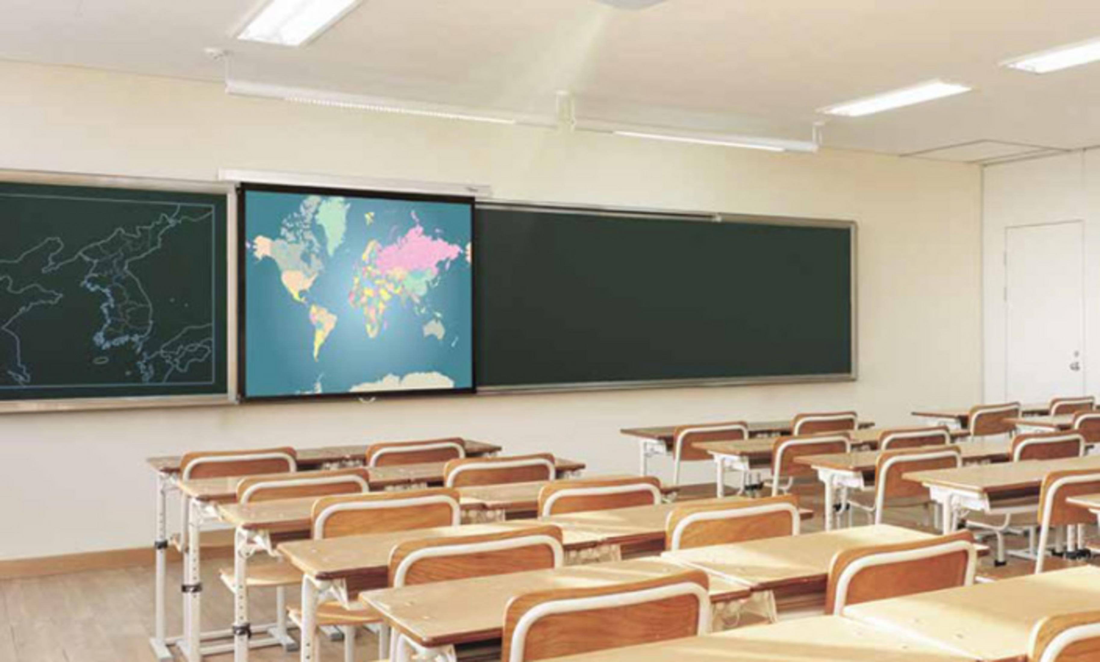 A classroom with desks and a chalkboard. A projector screen displays a world map.