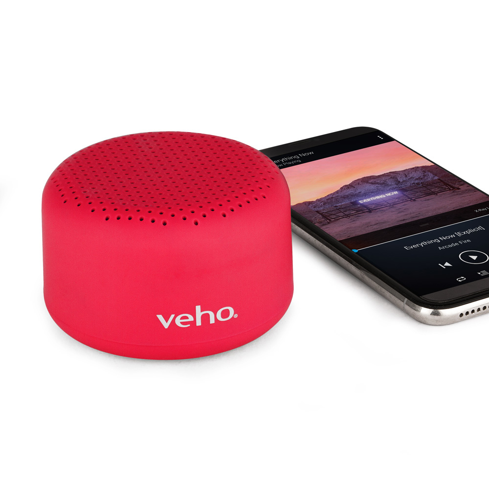 Altoparlante Veho rosso accanto a uno smartphone che riproduce musica.