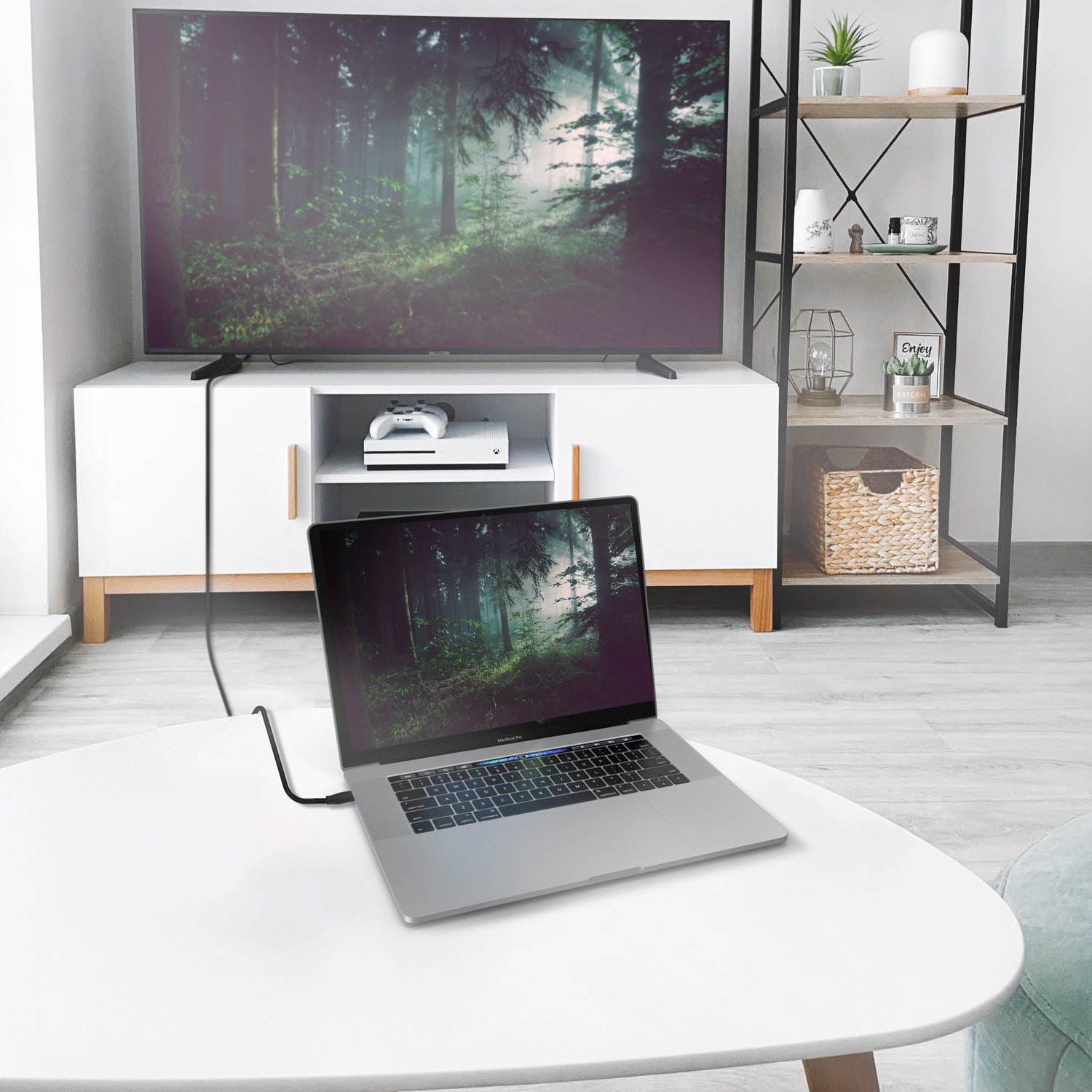 Portátil en una mesa conectado a un televisor. El televisor muestra una escena de bosque.