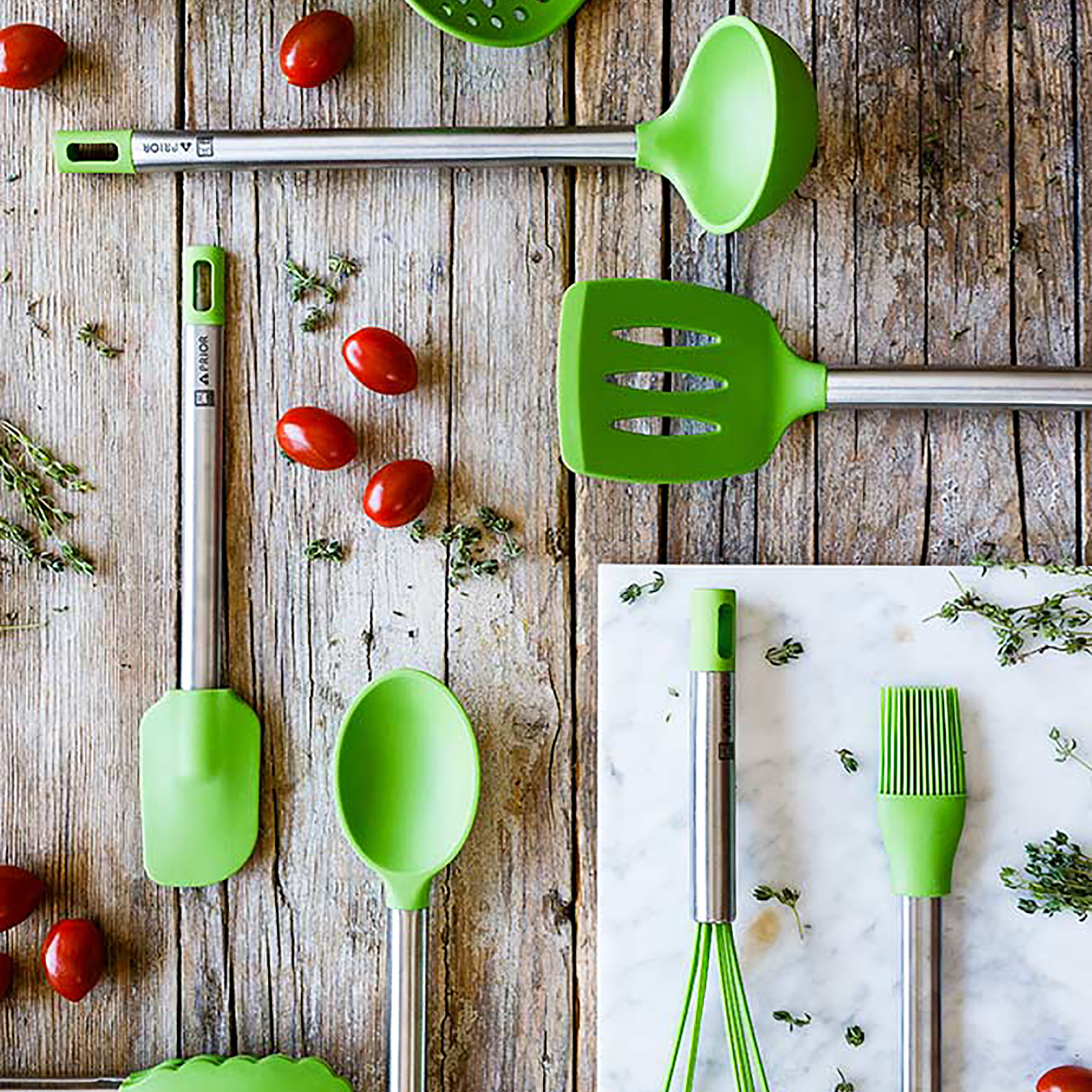 Widok z góry na przybory kuchenne: zielona łyżka, szpatułka, chochla, trzepaczka i pędzel na drewnianej powierzchni.