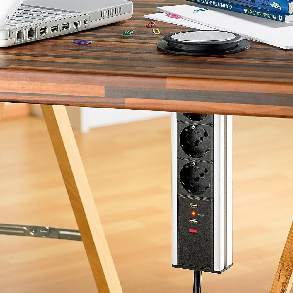 Multipresa con prese e porte USB sotto un tavolo di legno. La multipresa è verticale.