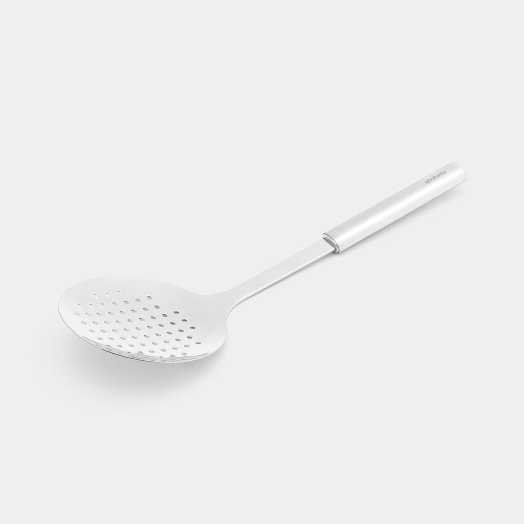 Cucchiaio forato argentato con molti fori. È su sfondo bianco.