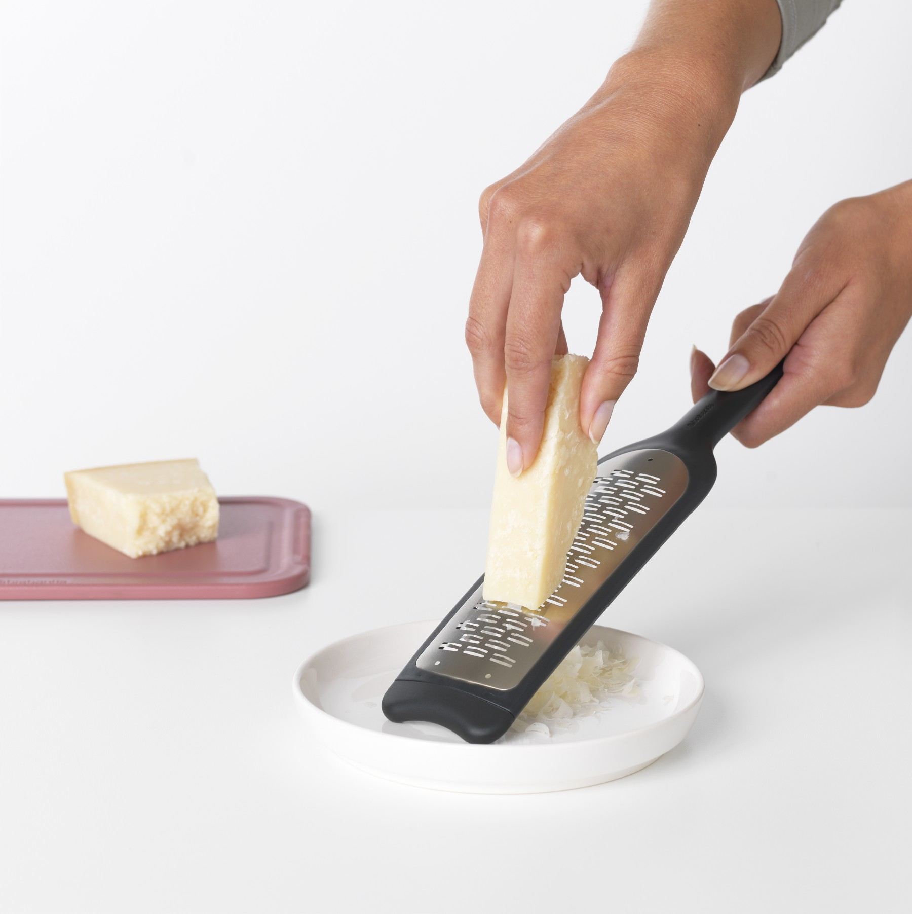 Hände, die Käse reiben. Reibe und Käse. Weißer Hintergrund.