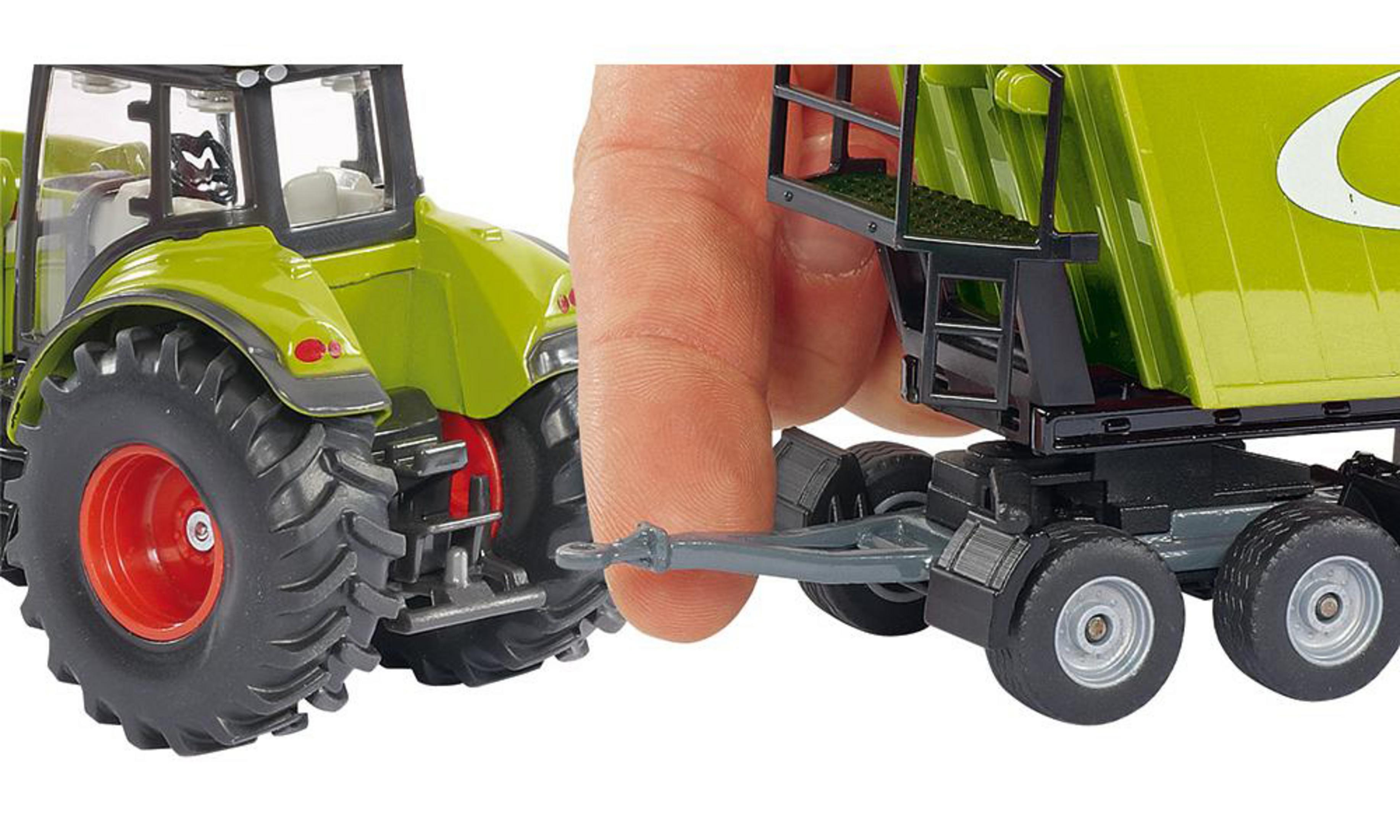 Eine Hand verbindet einen grünen Traktor mit einem grünen Anhänger. Der Anhänger hat einen schwarzen Sockel und Räder.