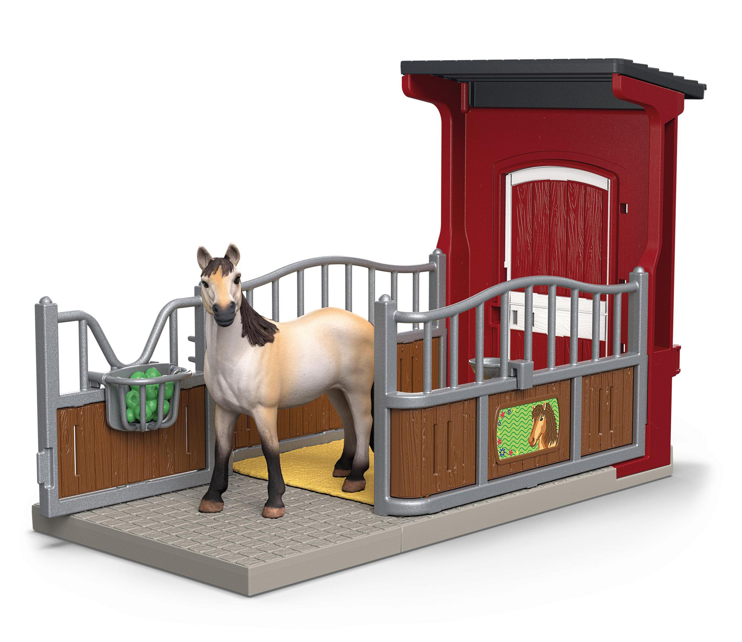 Cavallo giocattolo in una stalla rossa con una recinzione. Il cavallo è marrone chiaro e bianco.