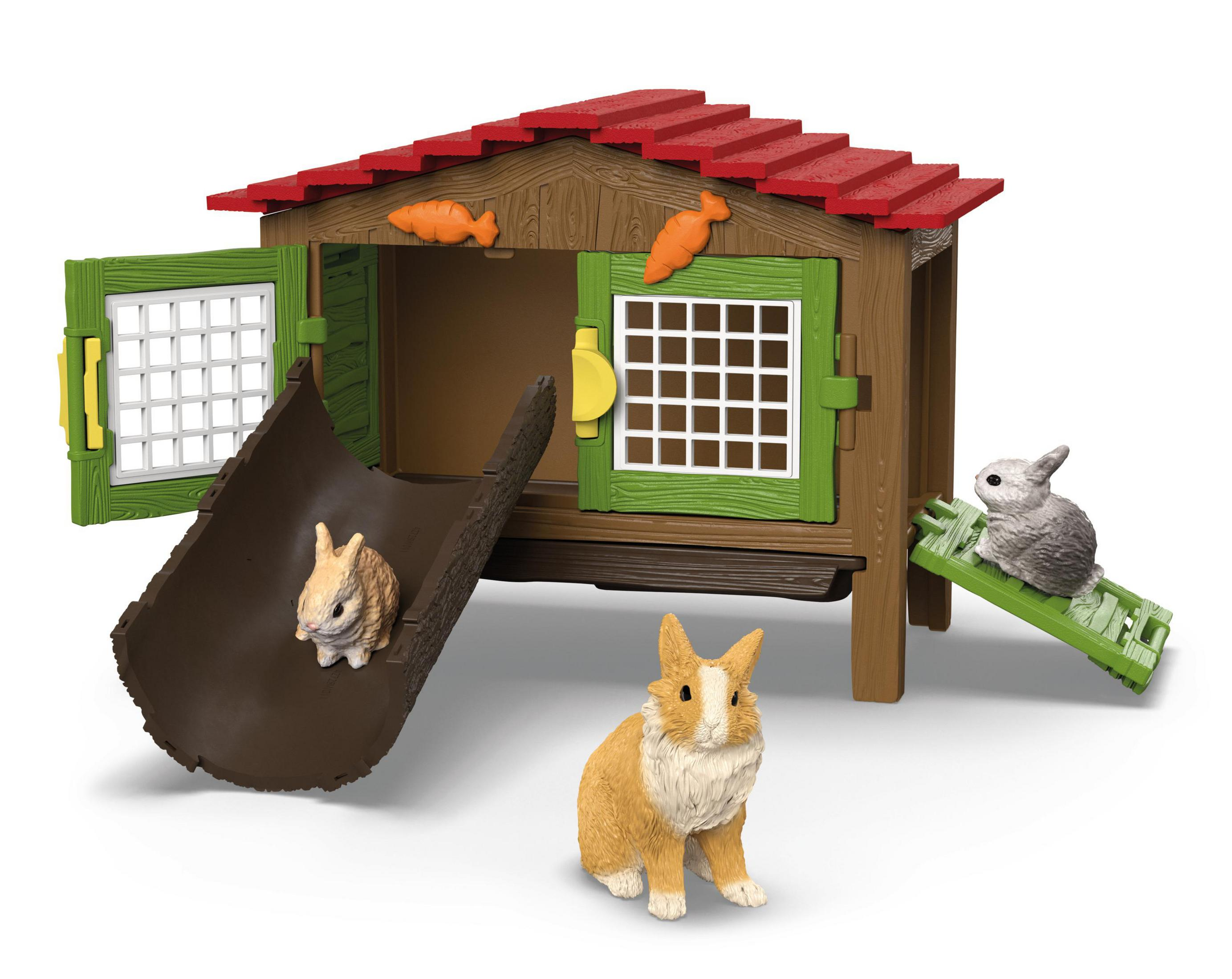 Ein Spielzeug-Kaninchenstall mit Kaninchen und Karotten. Der Hintergrund ist weiß.