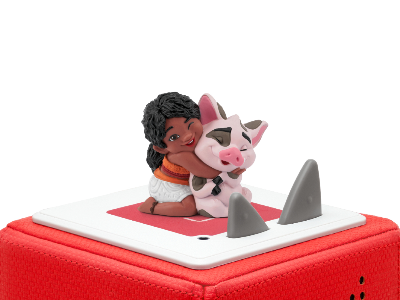 Moana umarmt eine Schweinefigur auf roter Oberfläche. Weißer Hintergrund.