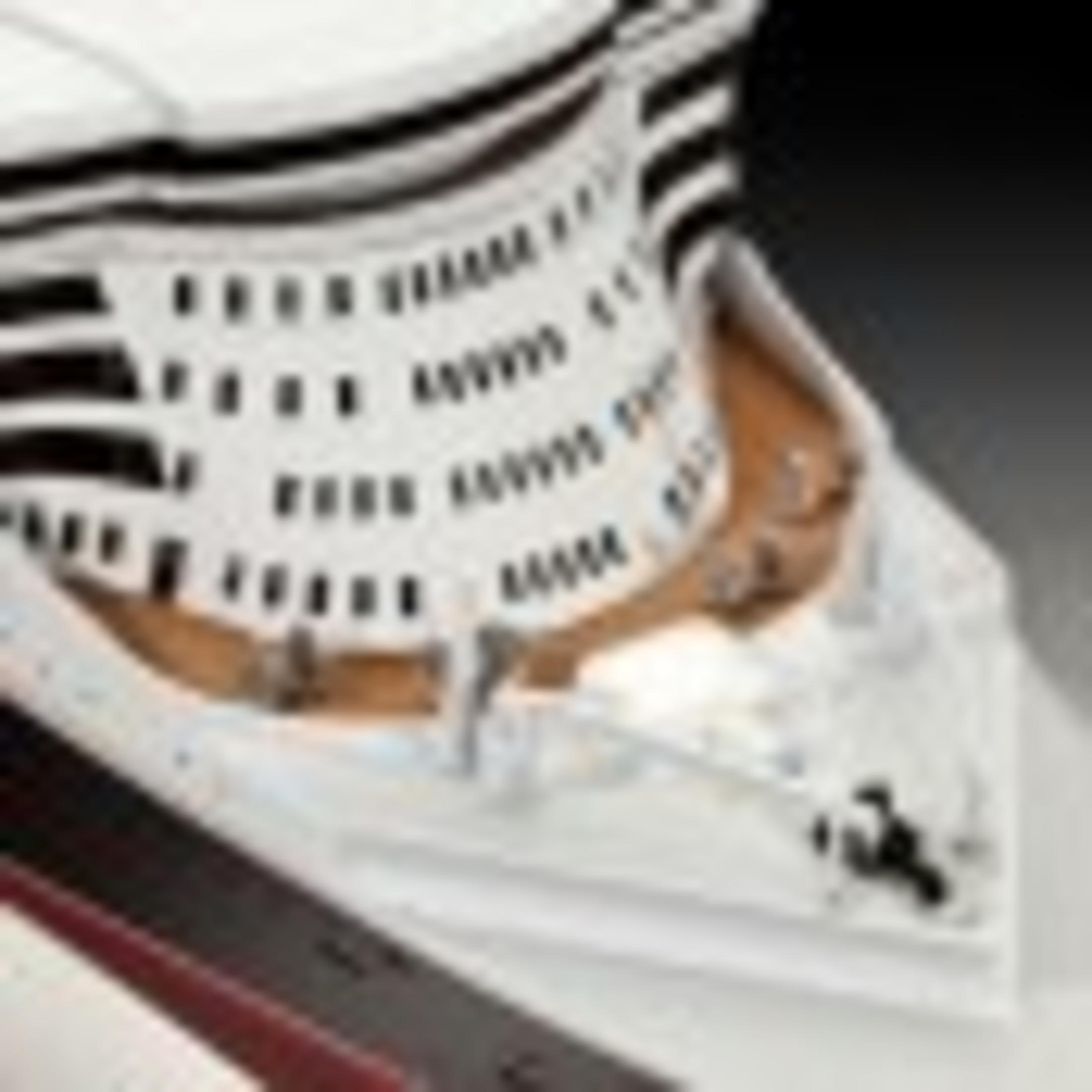 Close up of a white, multi-tiered cake with decorative, rectangular cutouts.