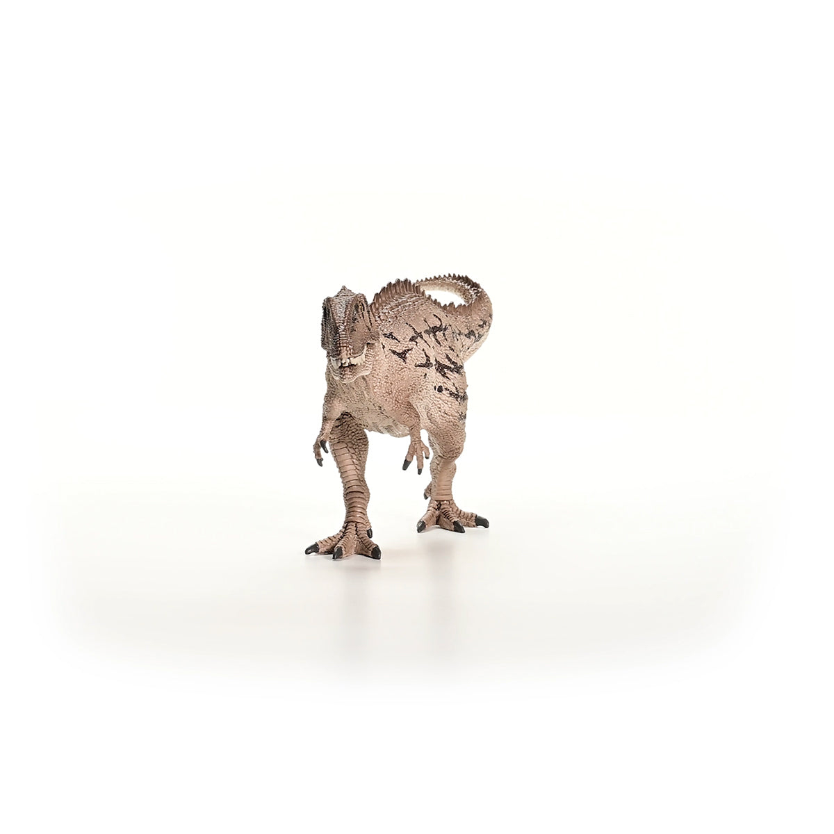 Juguete de dinosaurio marrón de pie sobre un fondo blanco. El dinosaurio mira a la cámara.