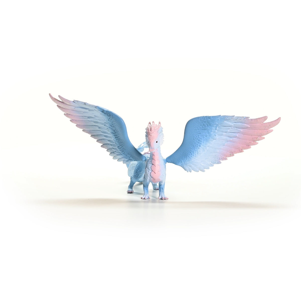 Un drago giocattolo con ali spiegate, sfumatura blu e rosa. Sfondo bianco.