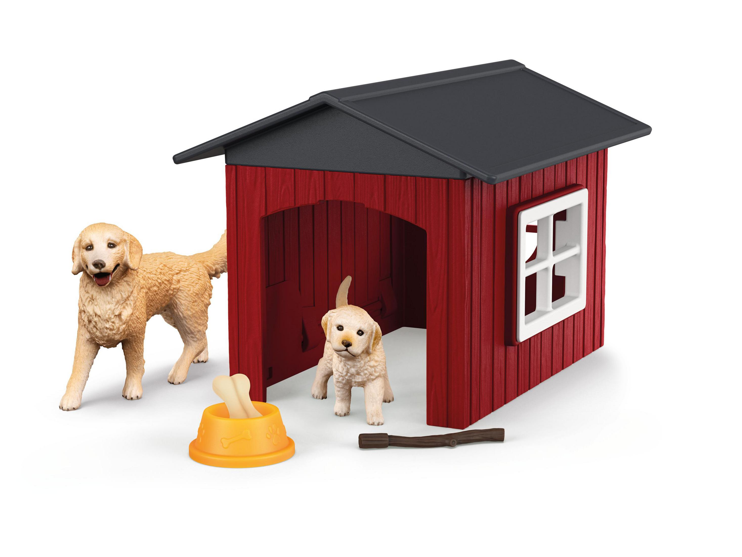 Giocattolo casetta per cani rossa, due cani, un osso e una ciotola su sfondo bianco.