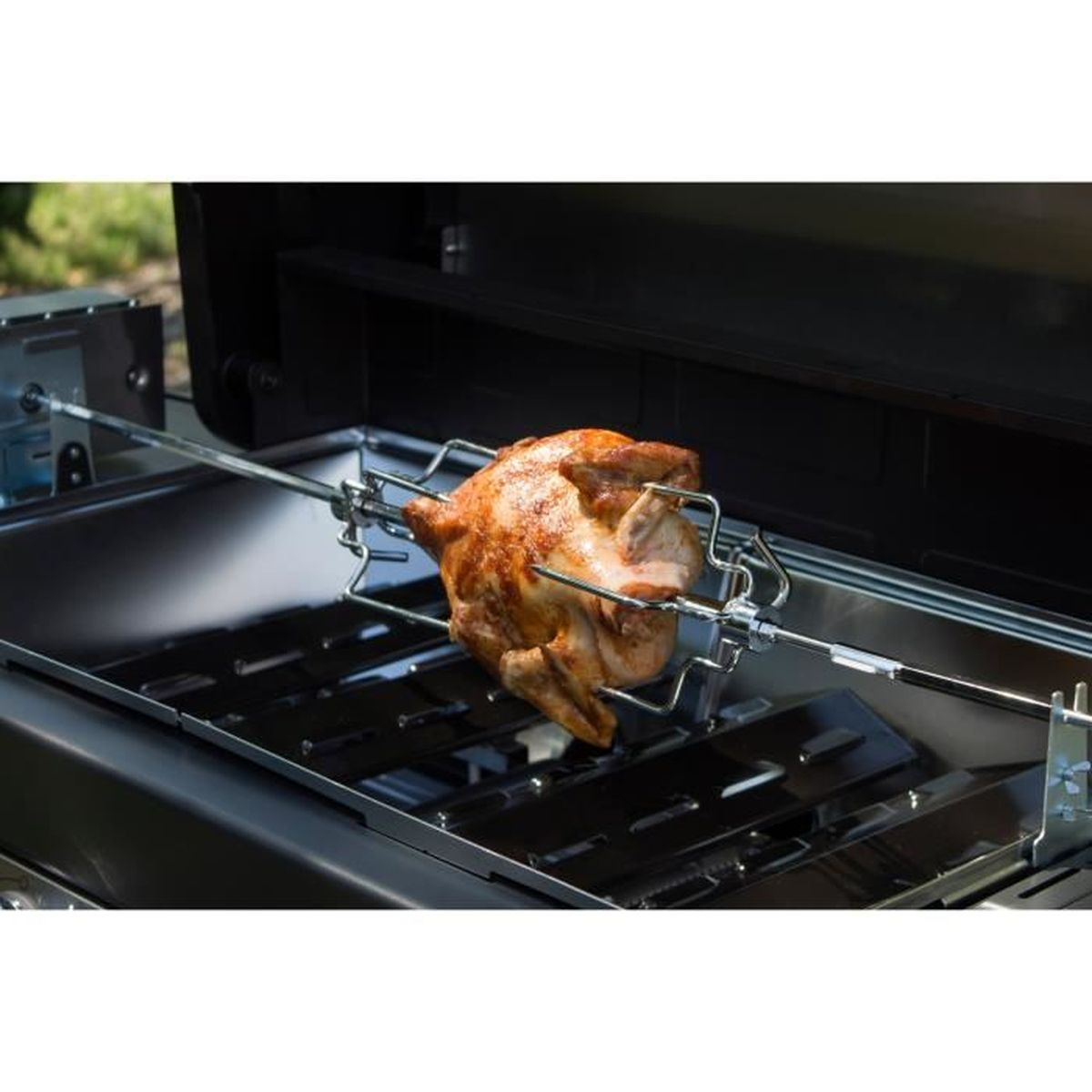 Pieczony kurczak na grillu. Grill znajduje się wewnątrz czarnego grilla. Zielone tło.