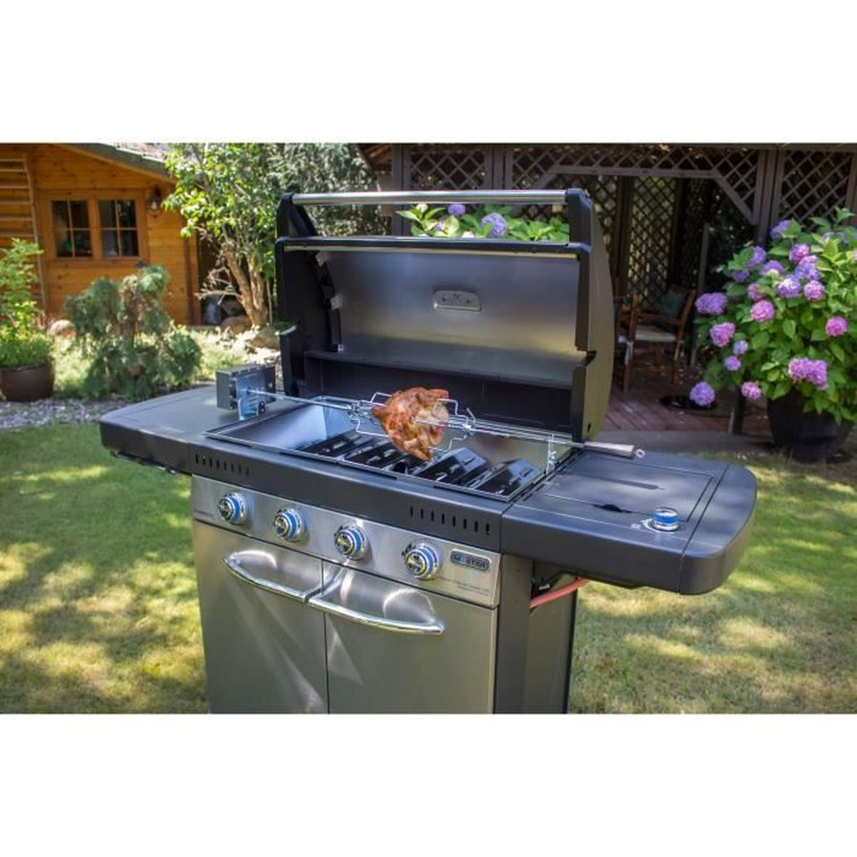 Grill ze stali nierdzewnej z pieczonym kurczakiem na rożnie, w ogrodzie.
