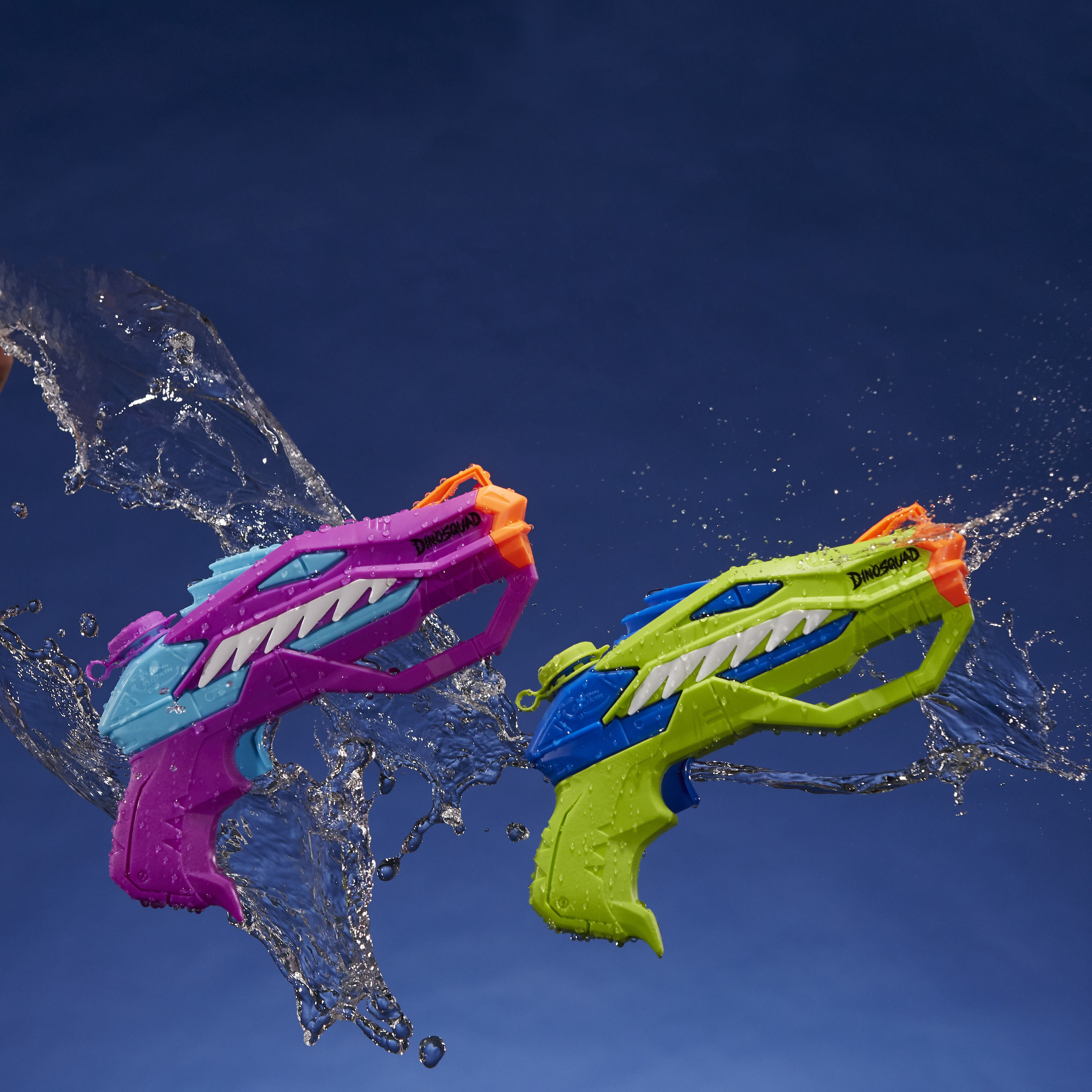 Dwa pistolety na wodę w kształcie dinozaurów strzelają wodą. Jeden jest fioletowy, drugi zielony. Niebieskie tło.